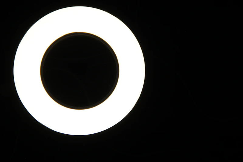 Glowing white circular ring light against a black studio backdrop.