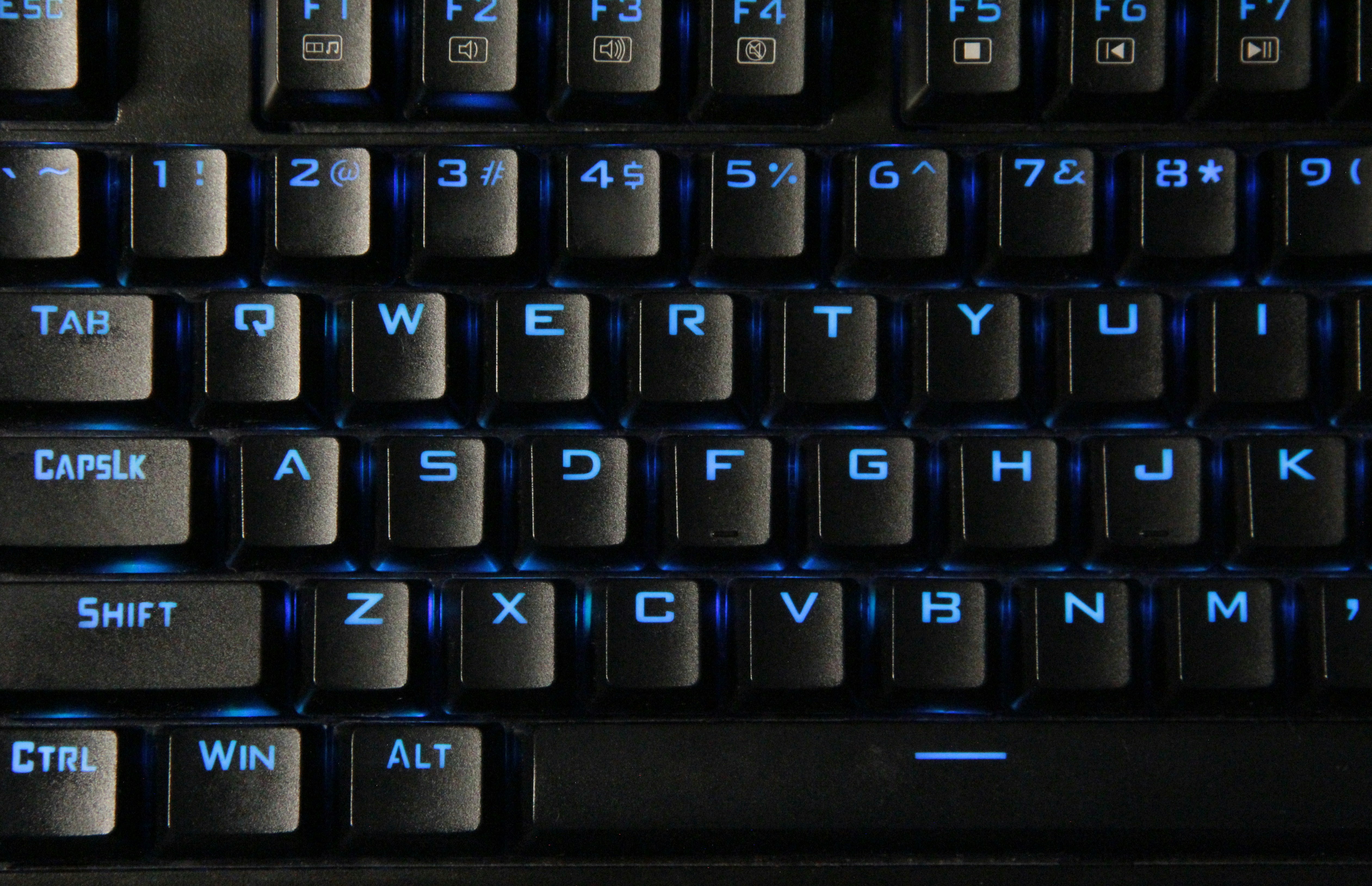 Primer plano de un teclado negro con retroiluminación azul.
