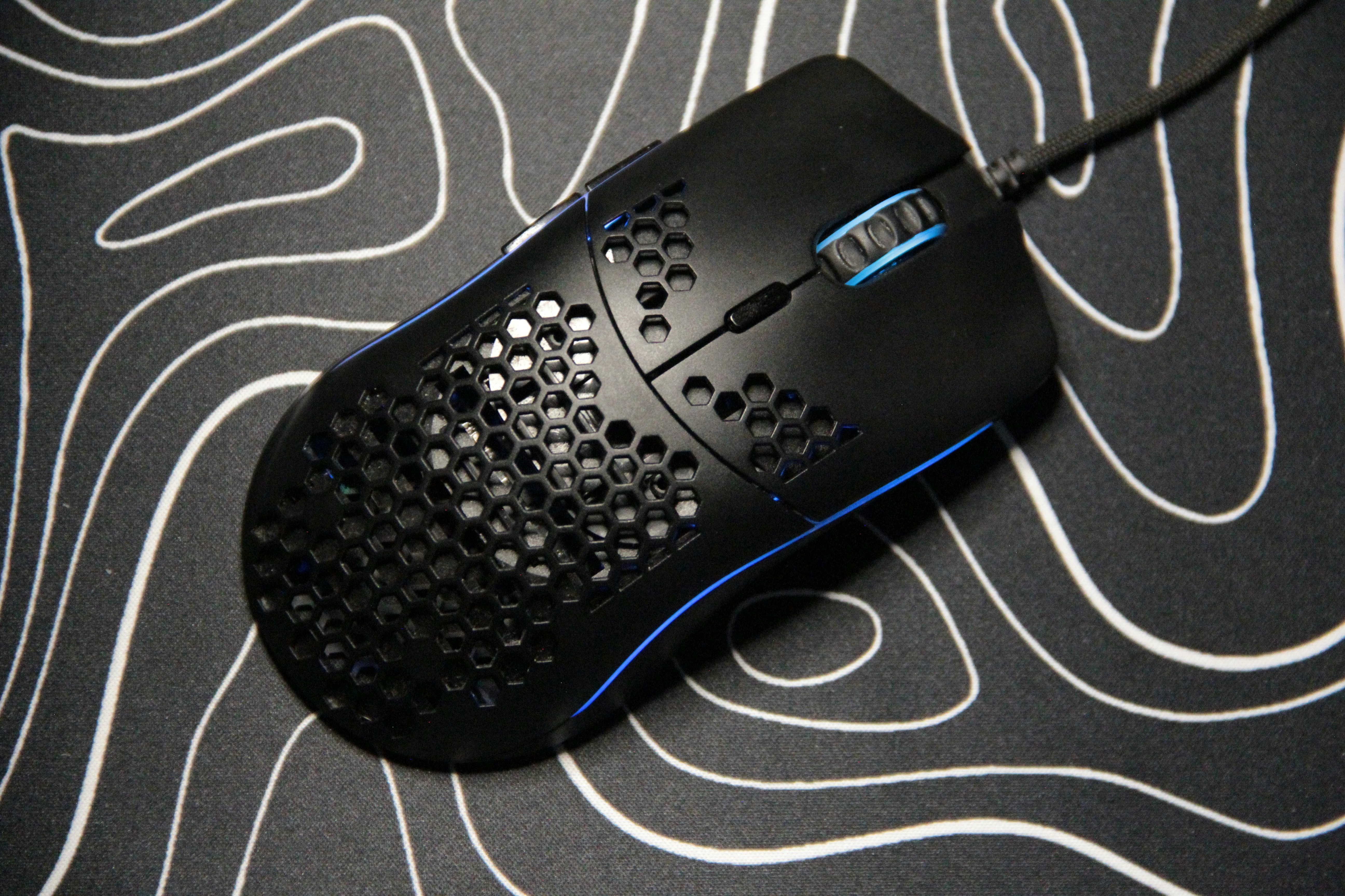A black gaming mouse with blue accents on a mat.