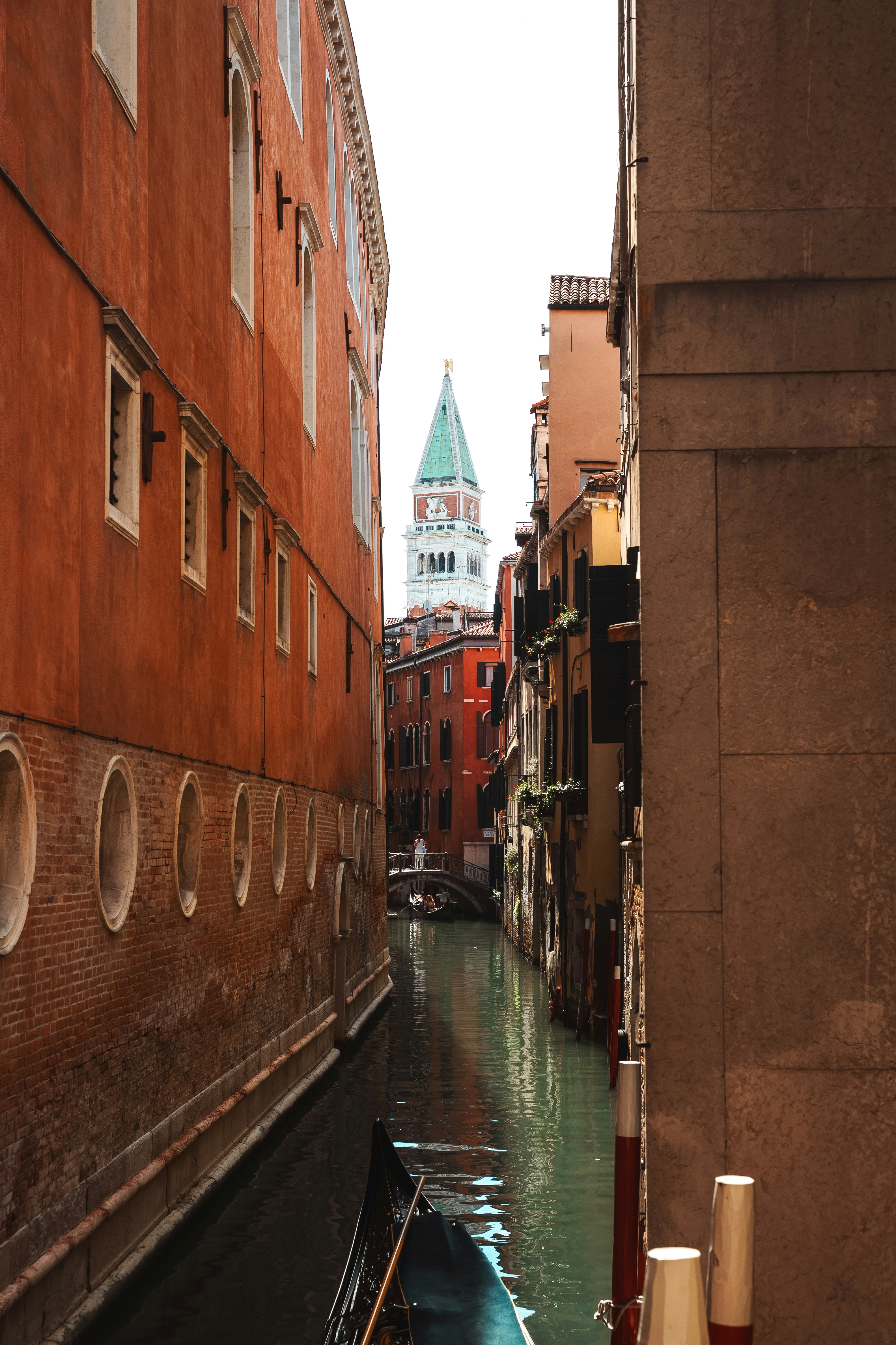 Narrow canal between buildings with a distant clock tower.