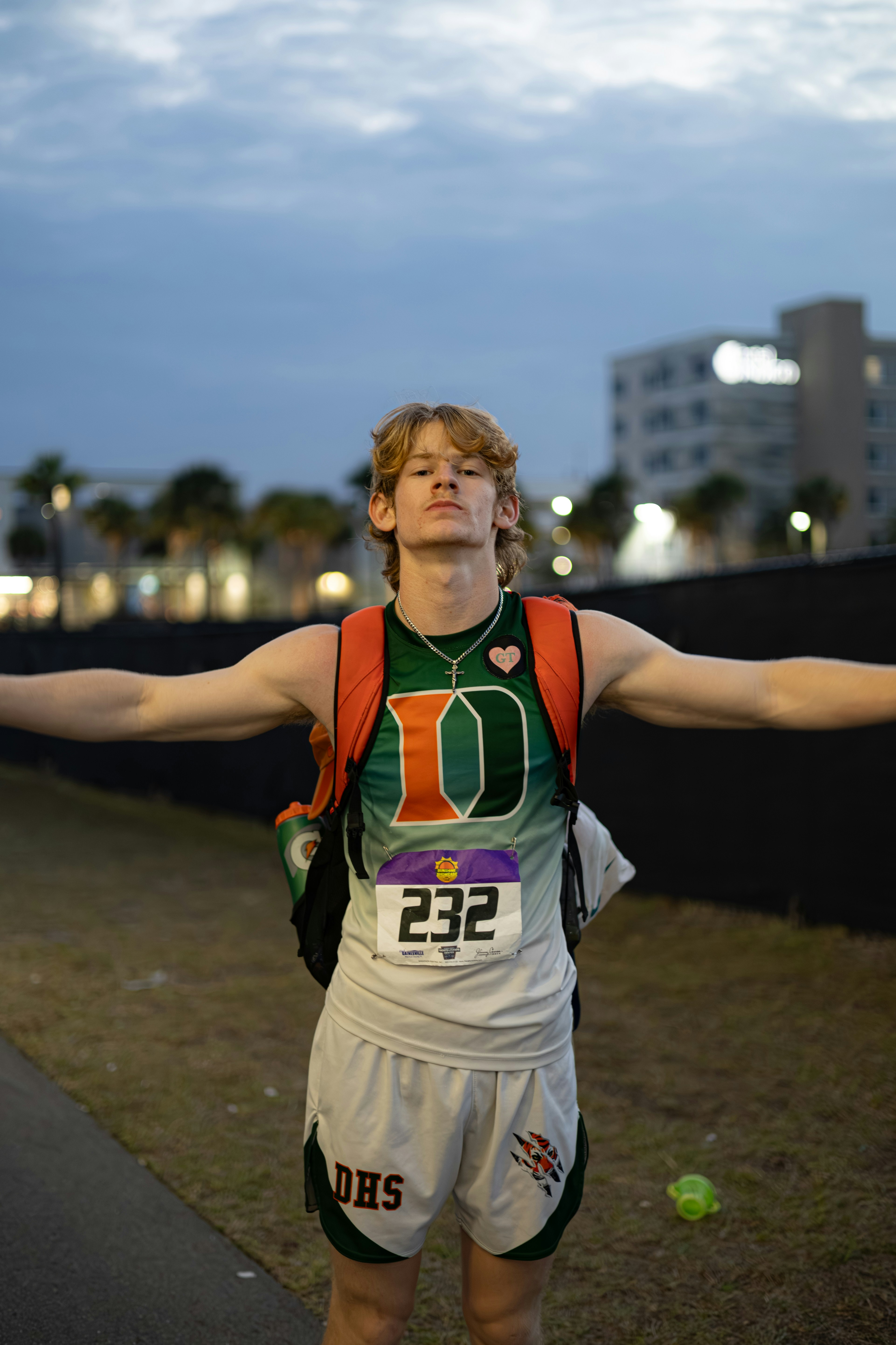 Teenage boy in running gear with arms outstretched