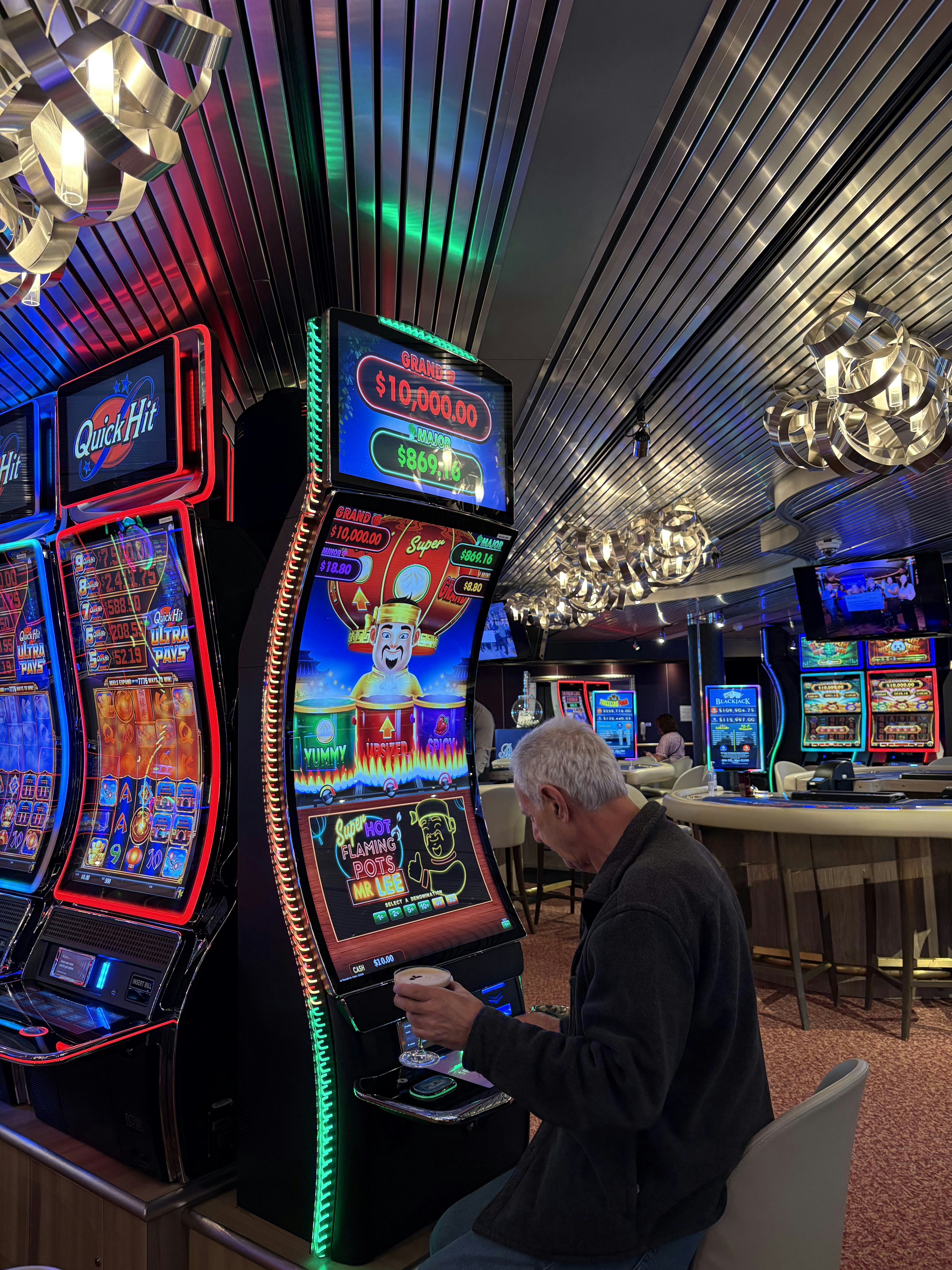 A man holding a cocktail while playing a slot machine in a casino