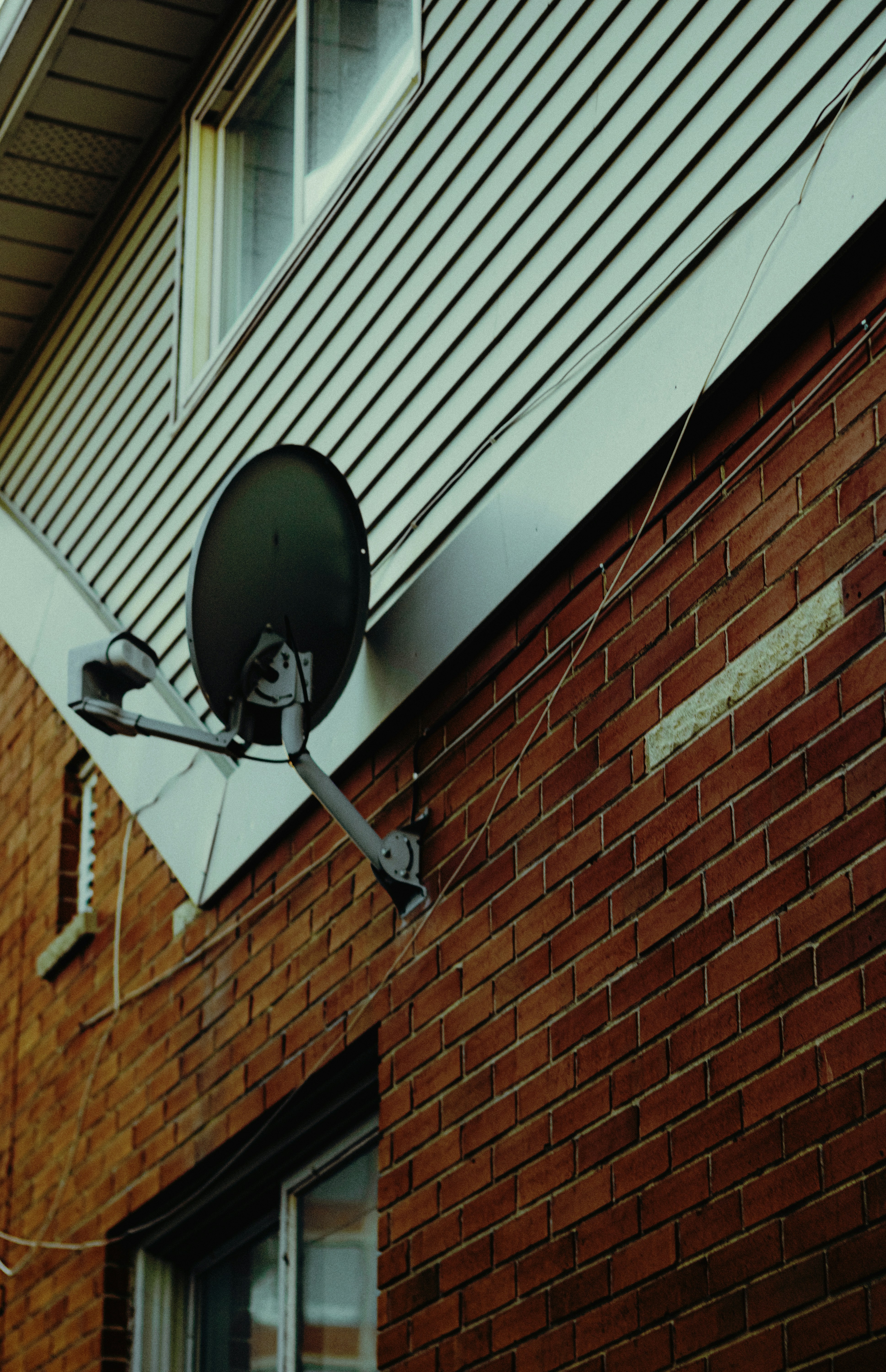 Satellite dish mounted on a brick wall.