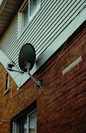 Satellite dish mounted on a brick wall.