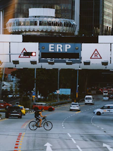Cyclist crosses road under erp gantries with traffic