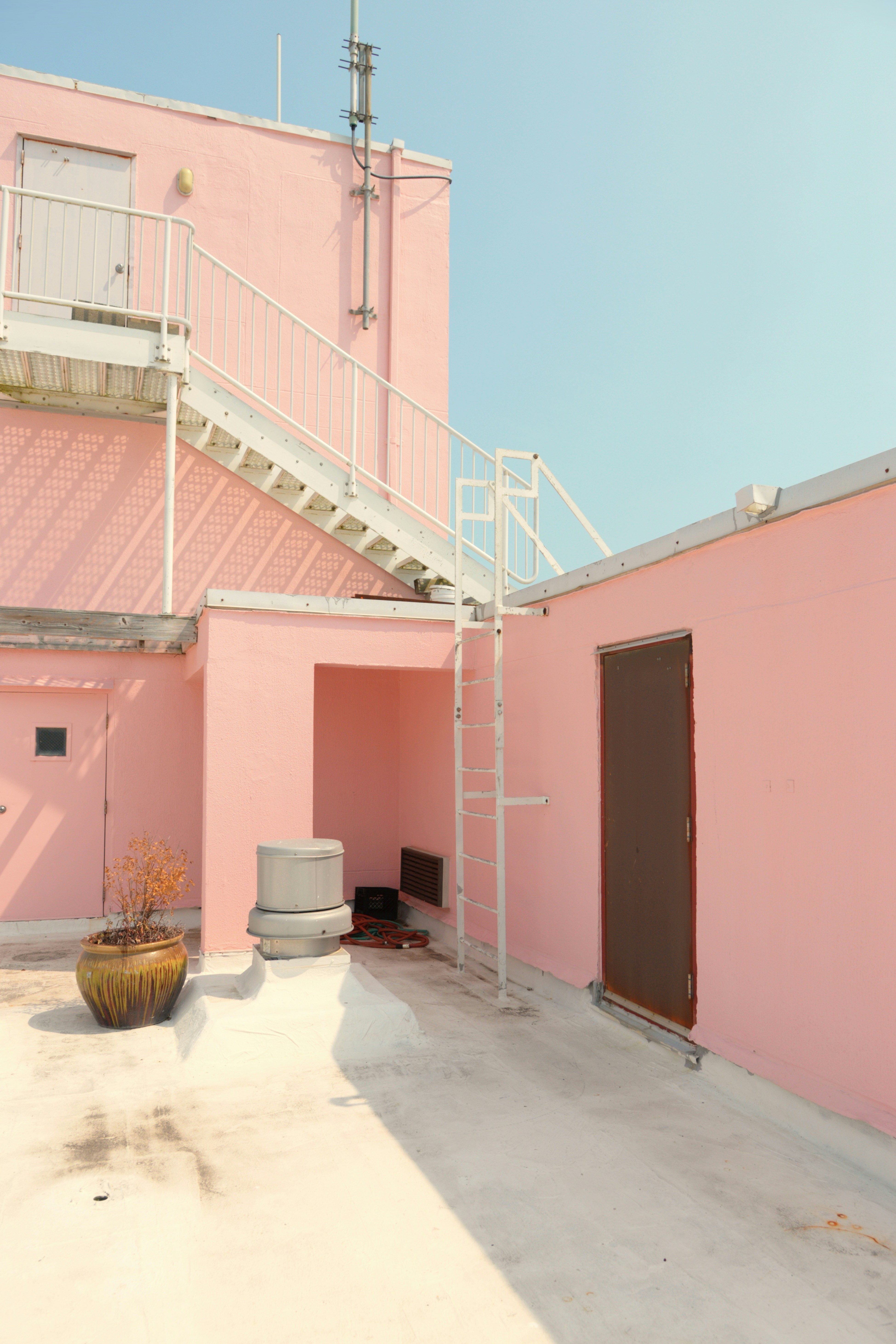 Pink building exterior with white stairs and doors.