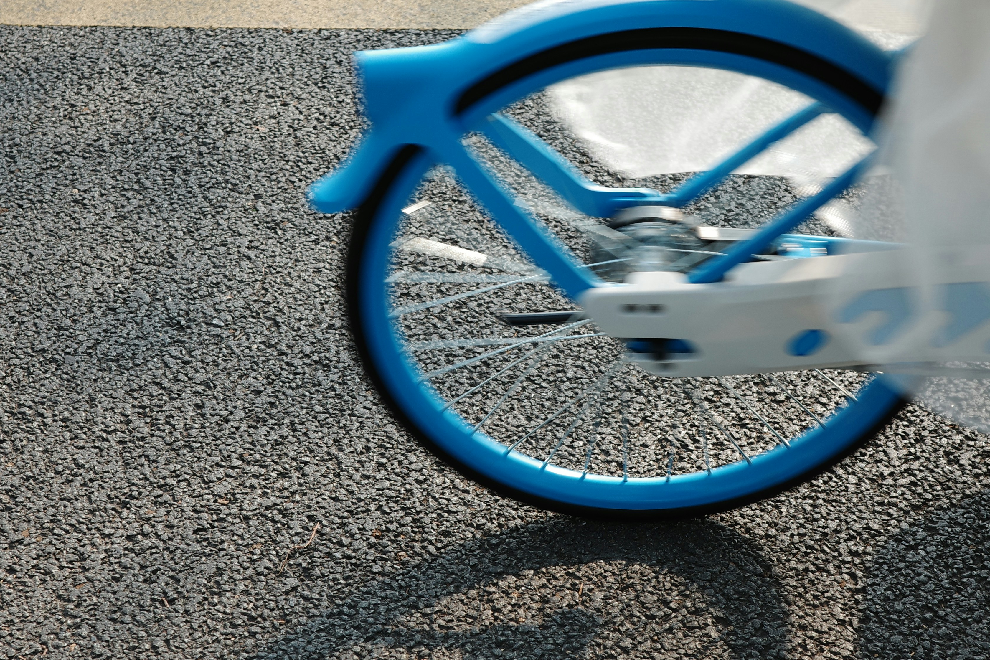 Blue bicycle wheel on a grey asphalt surface.