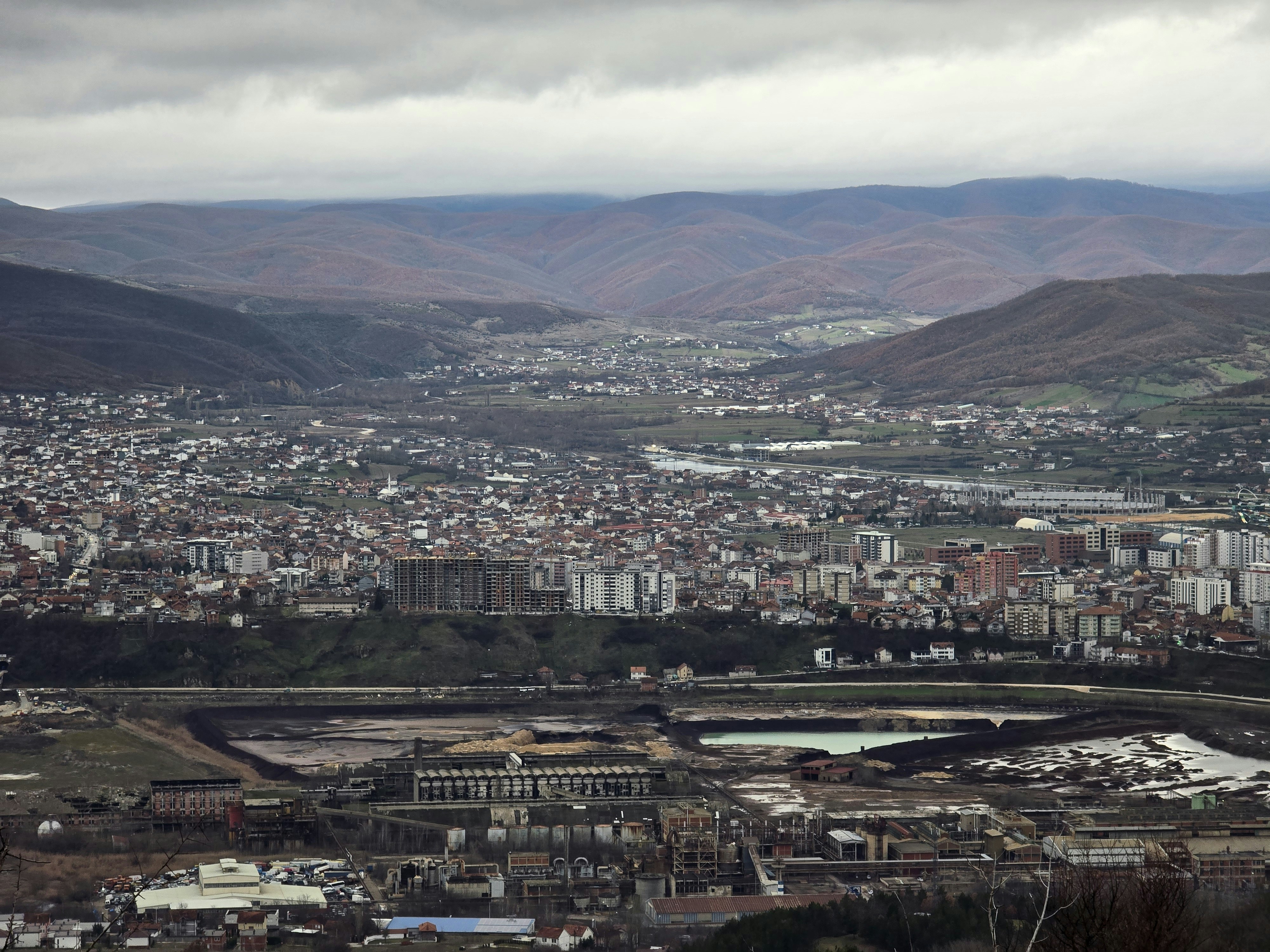 A sprawling city nestled in a valley between rolling hills.