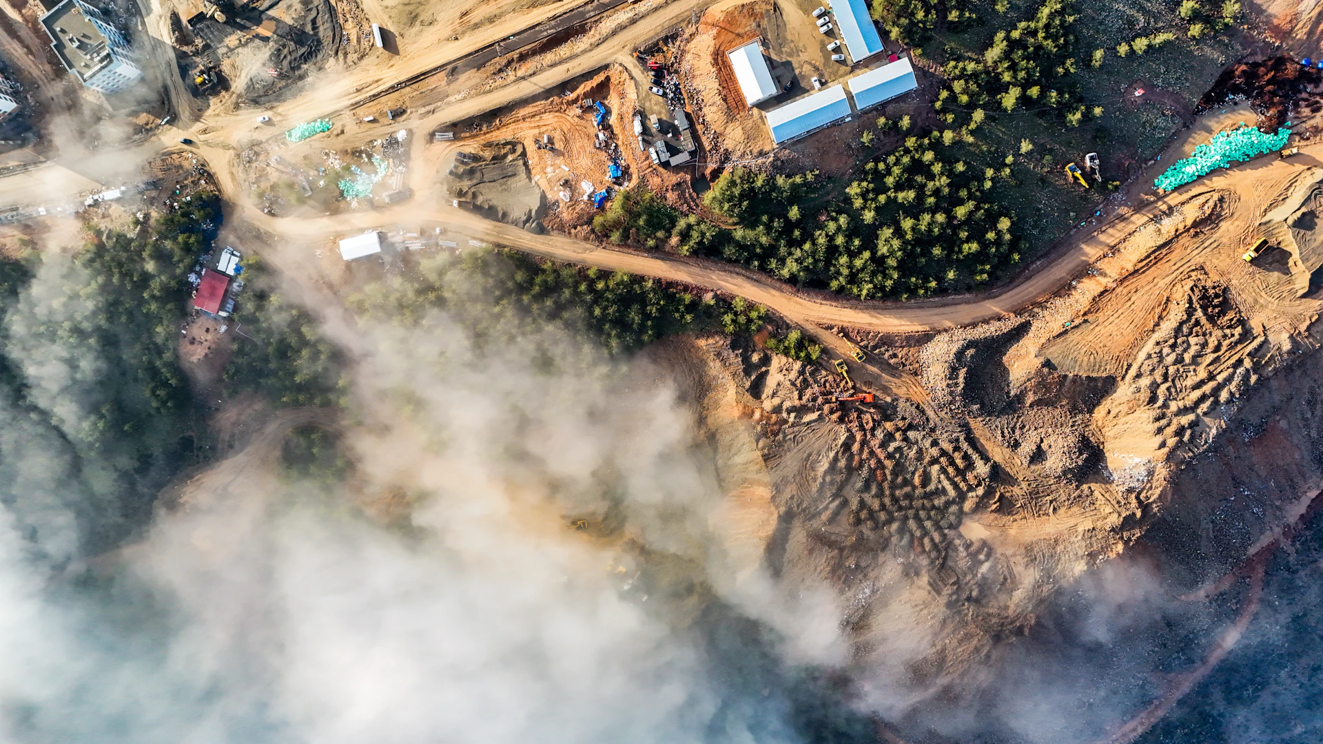 Aerial view of a construction site with clouds below.