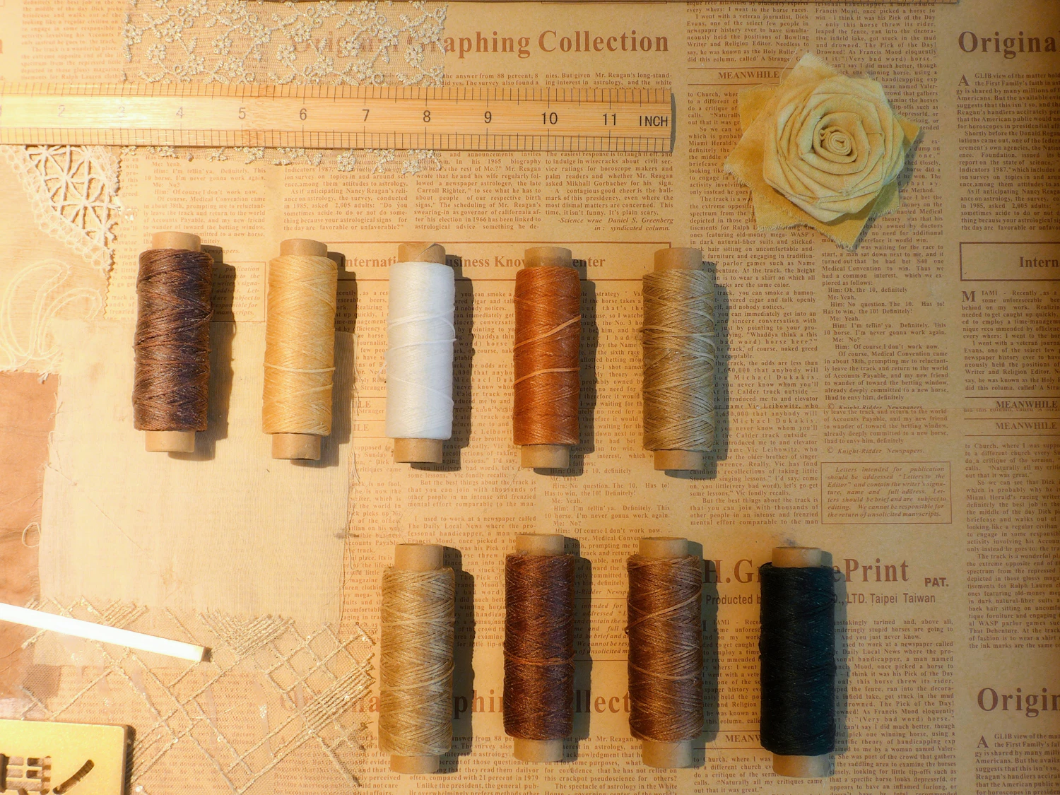 Spools of thread in brown, white and rust lined up on paper