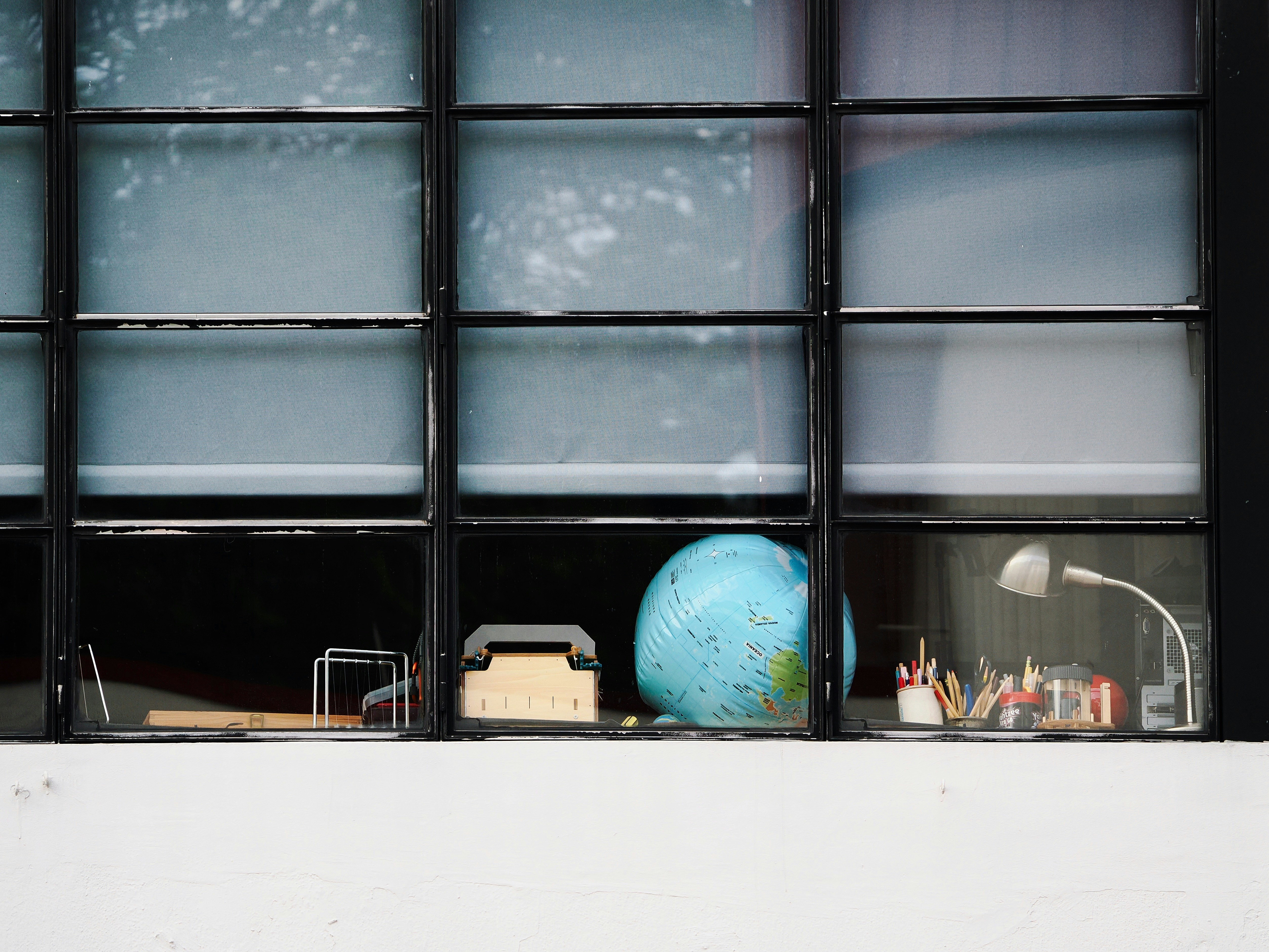 Desk with globe, lamp, and supplies by window.