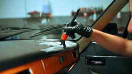 Detailer cleaning the dashboard of a classic car.
