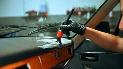 Detailer cleaning the dashboard of a classic car.