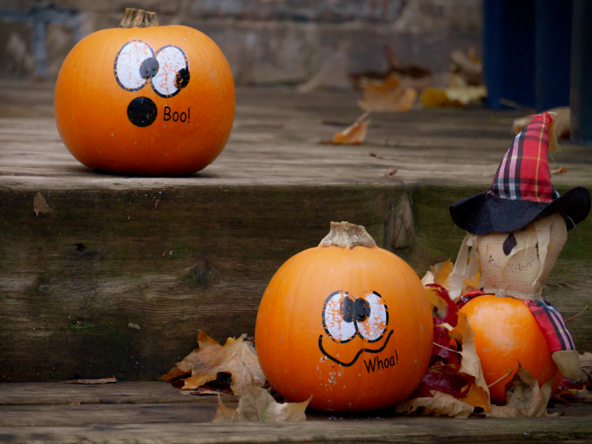 Pumpkins and a scarecrow on wooden front steps