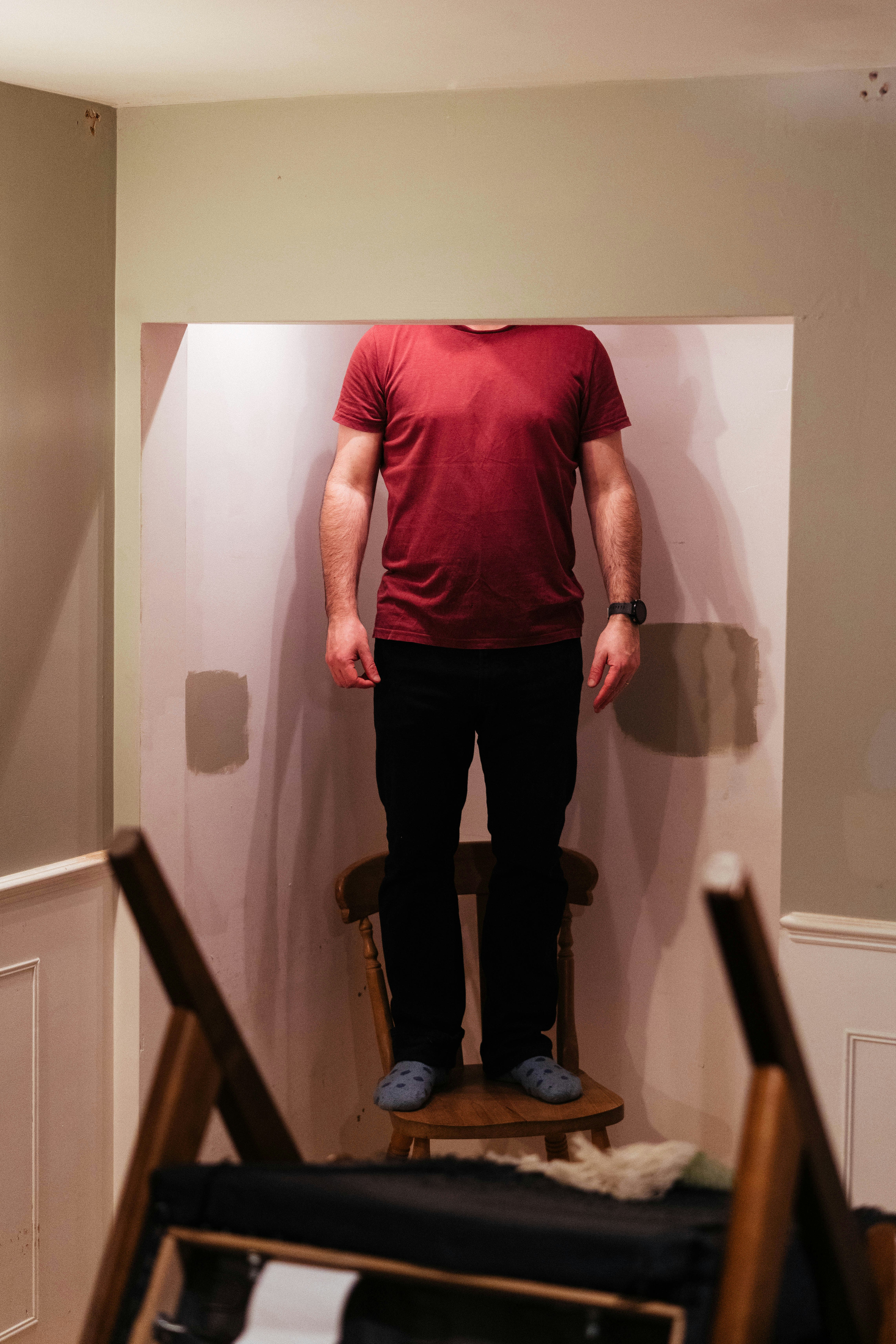 Man in red shirt standing on chair with no head