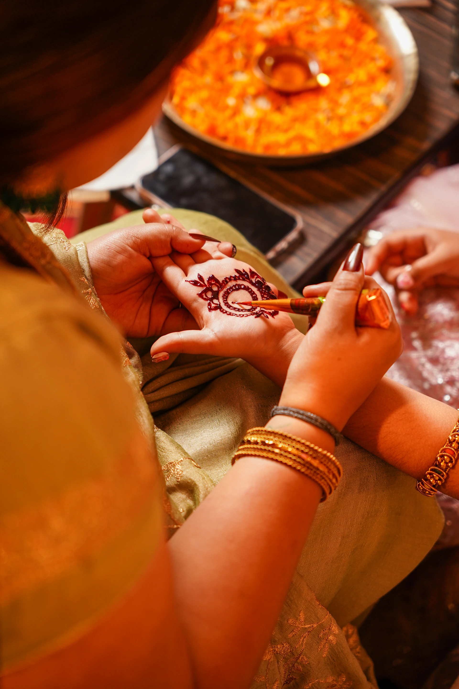 Artist applies henna design to a person's hand.