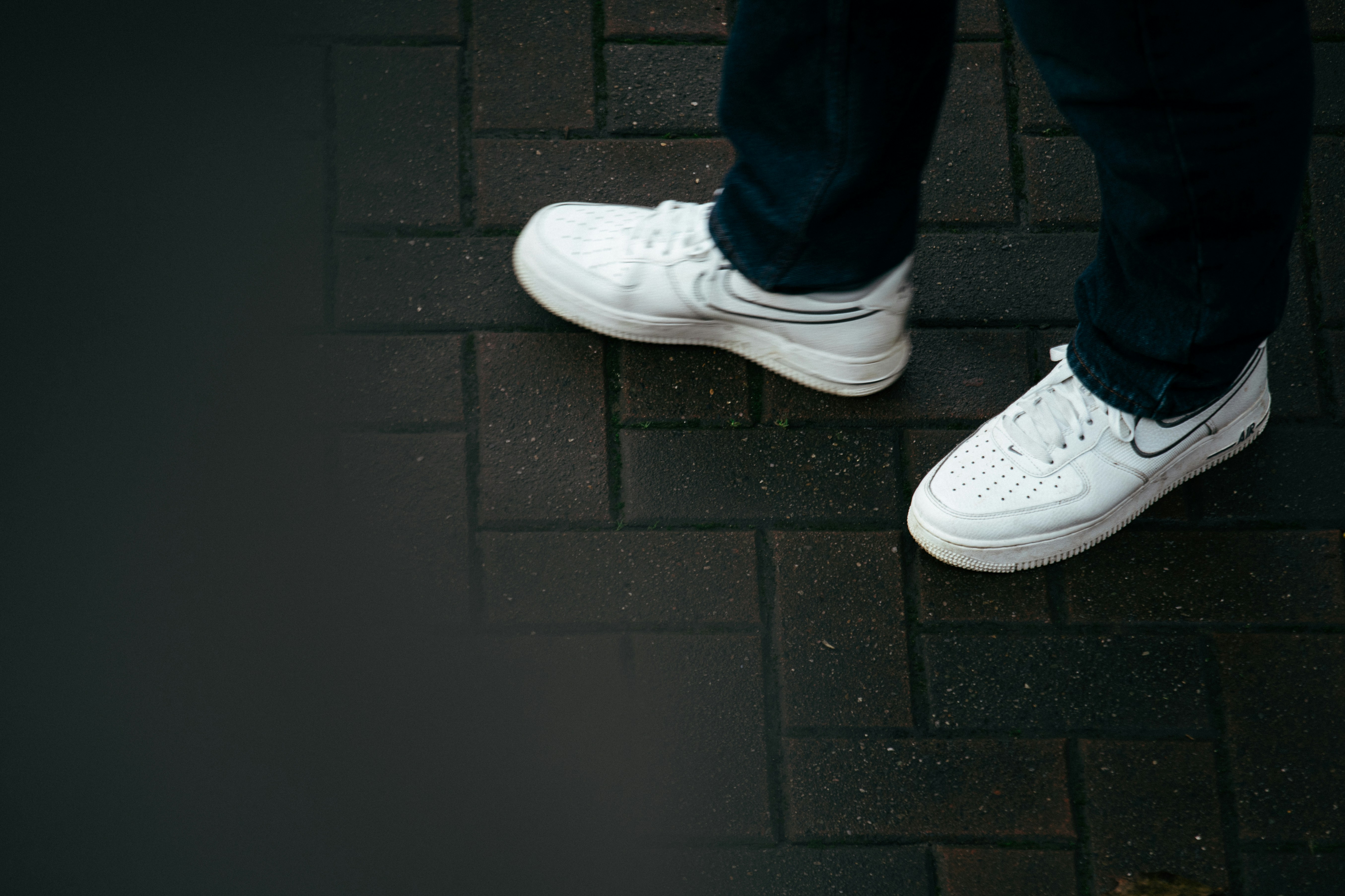 Person wearing white sneakers on a brick path