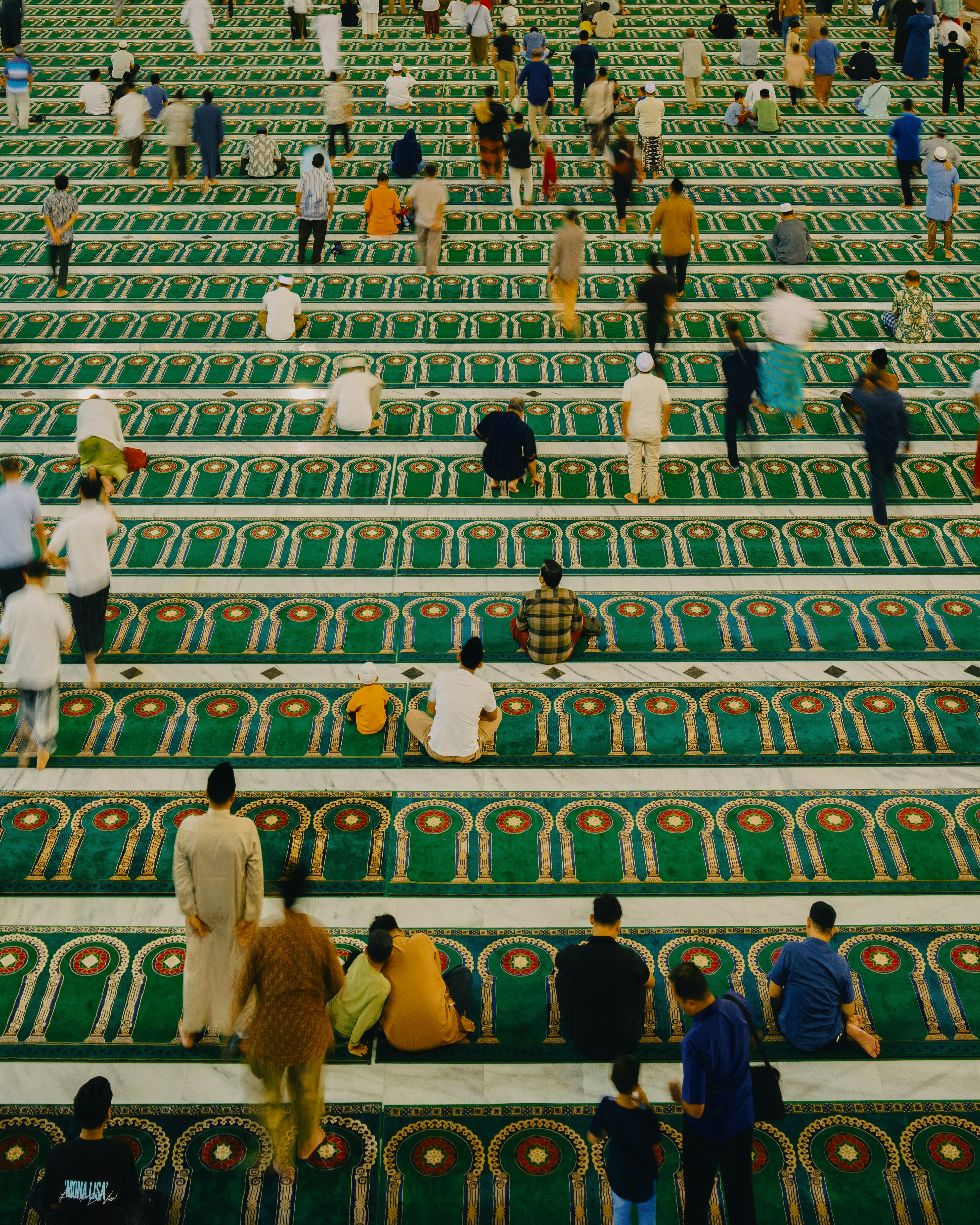 Menschen, die in Reihen auf einem gemusterten Teppich beten