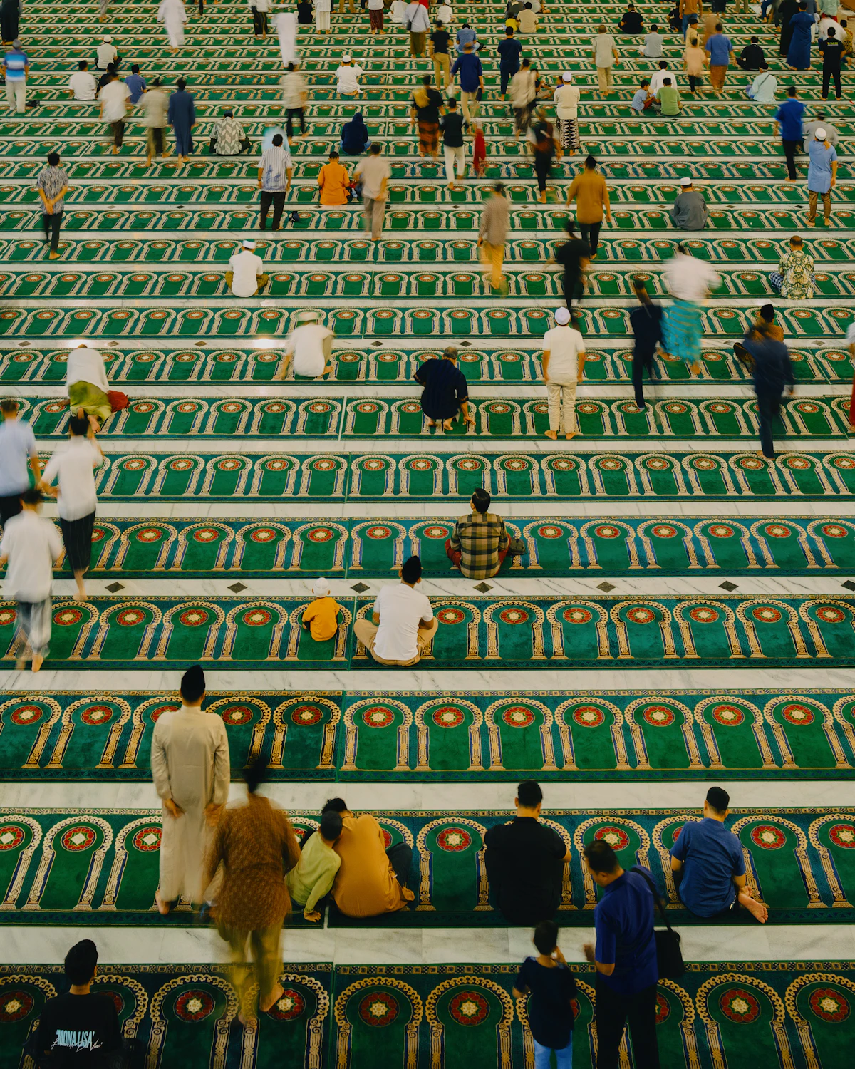 Jamaah salat berbaris di atas karpet bermotif.