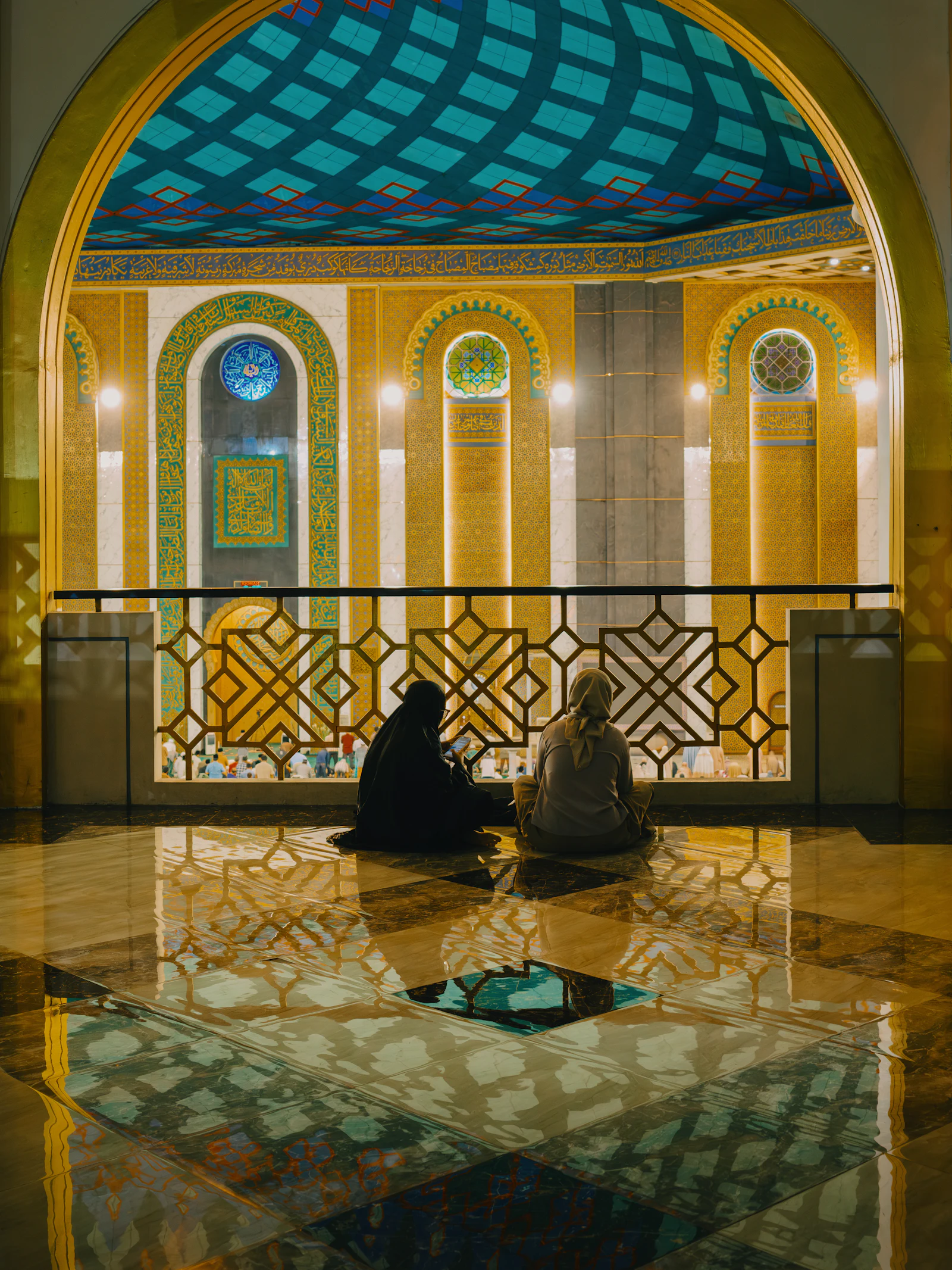 Two people sitting in an ornate masjid
