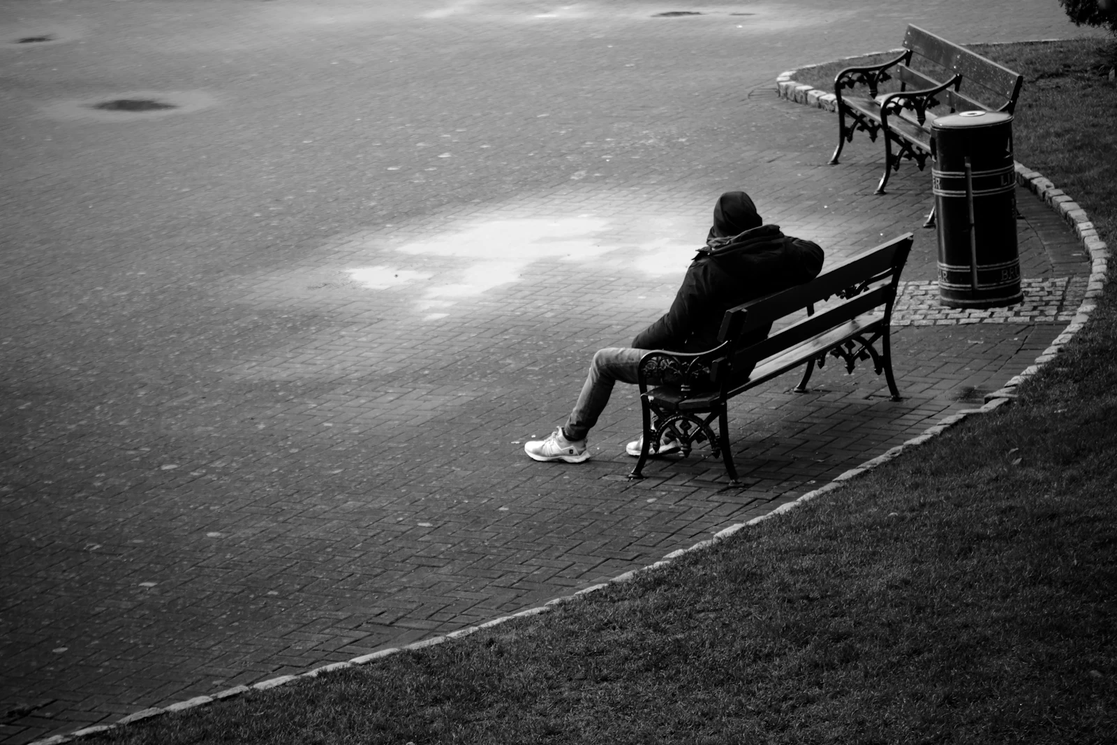 Person sitting alone on a park bench in the rain