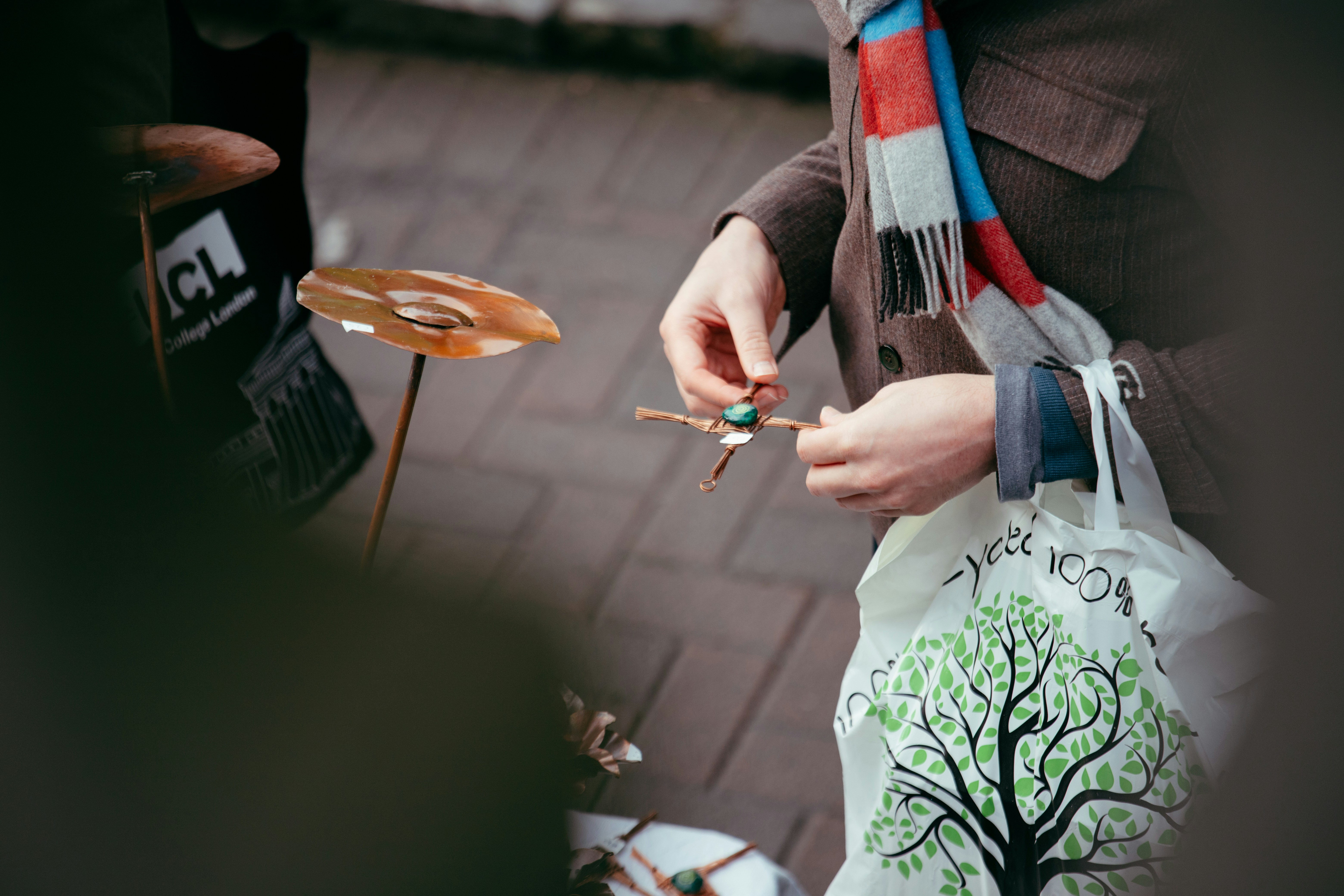 Person holding a small wooden ornament with a scarf.