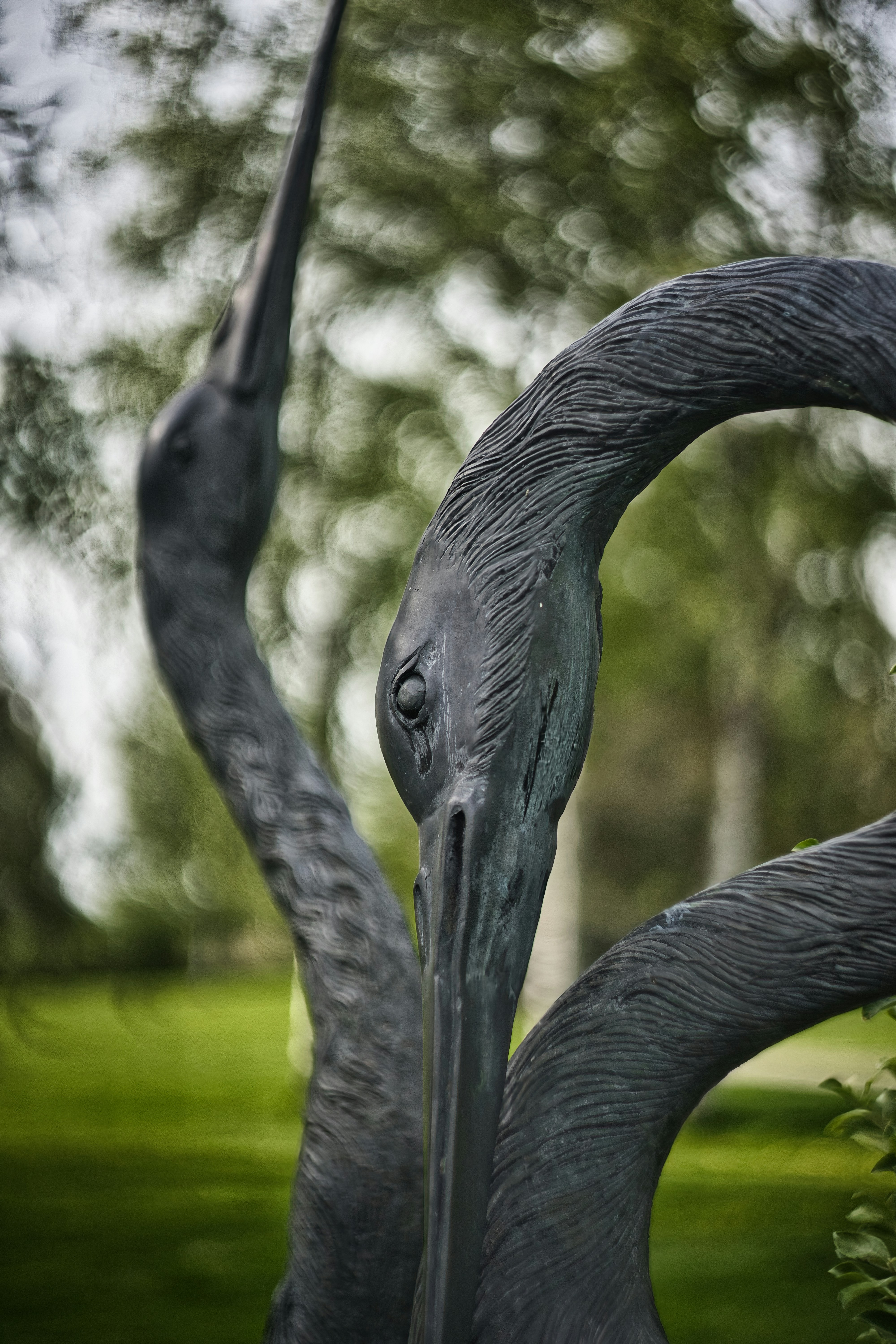 Bronze sculptures of three cranes in a garden