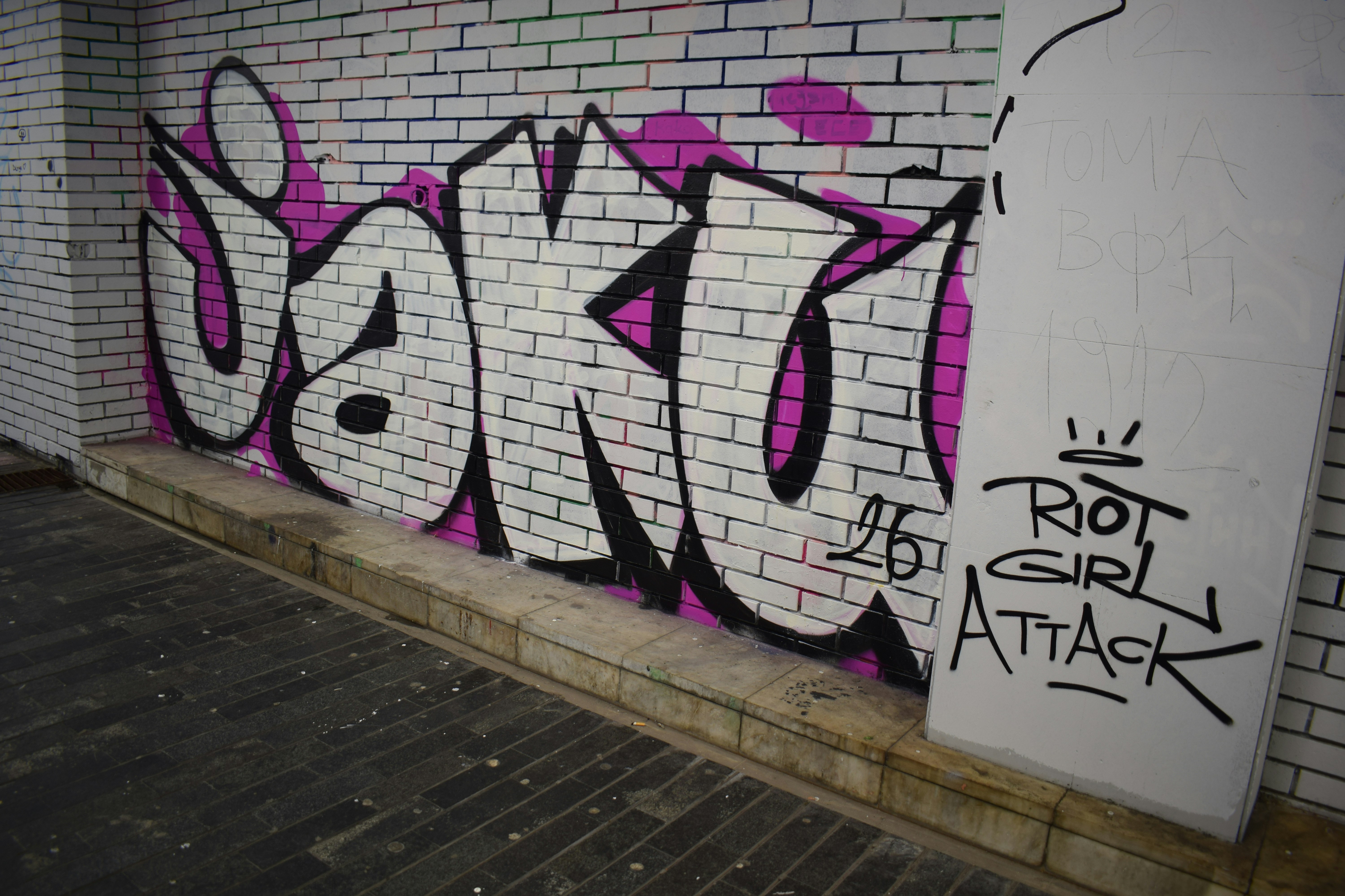 Graffiti art on a white brick wall with pink accents.