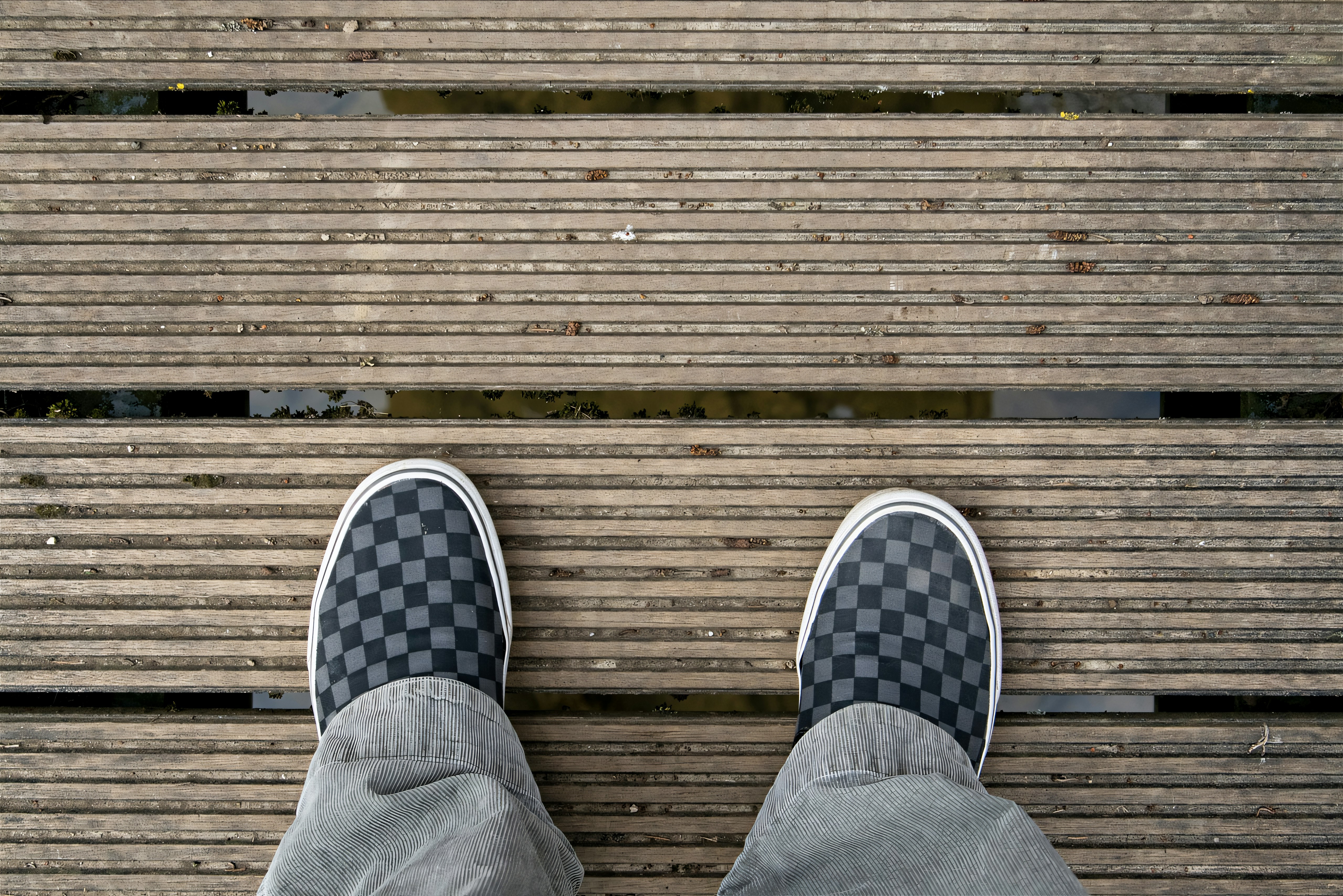 Feet in checkered shoes on a wooden walkway