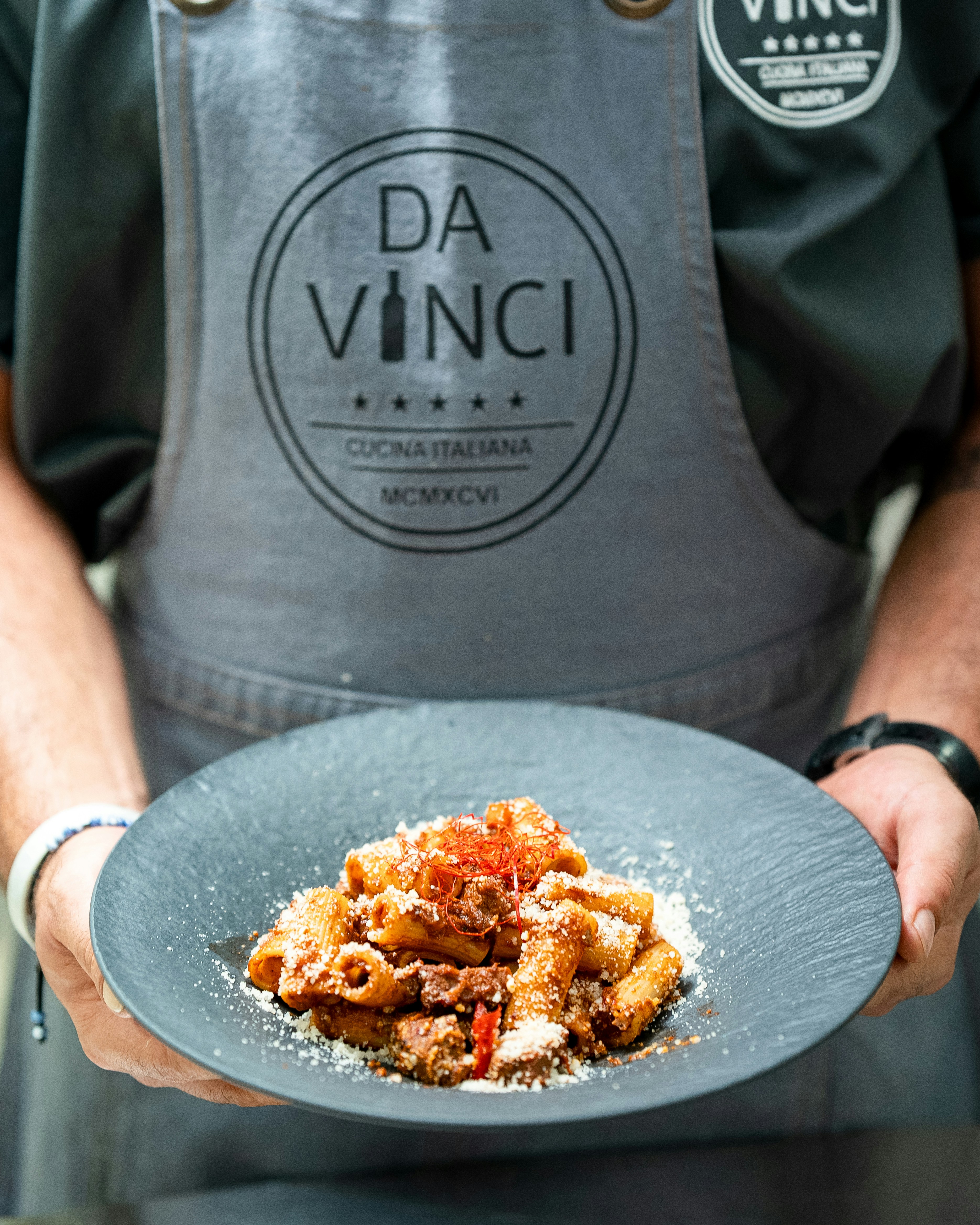 Der Koch präsentiert einen Teller Pasta mit Soße