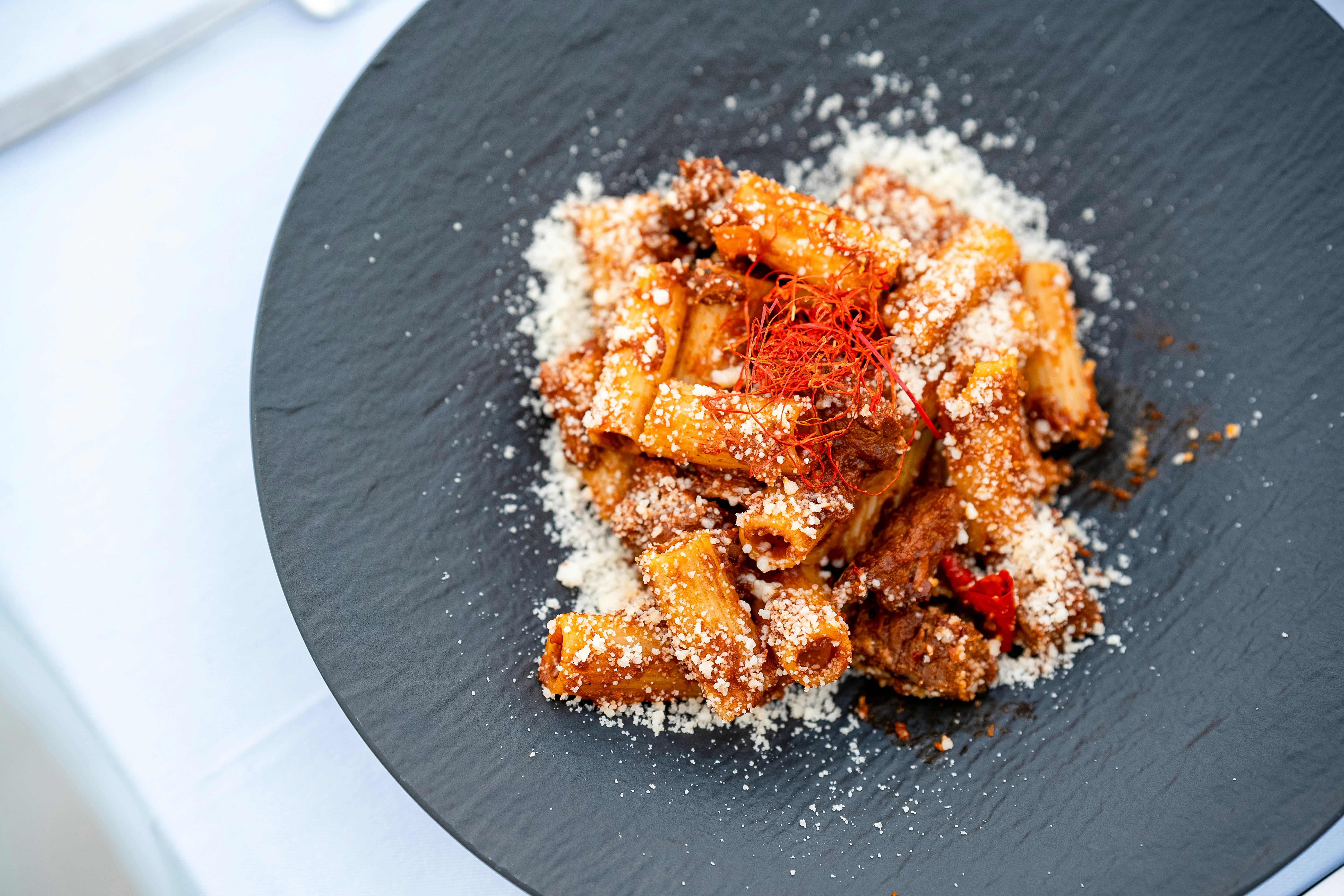 Rigatoni-Pasta mit Fleischsoße und Käse auf einem Teller
