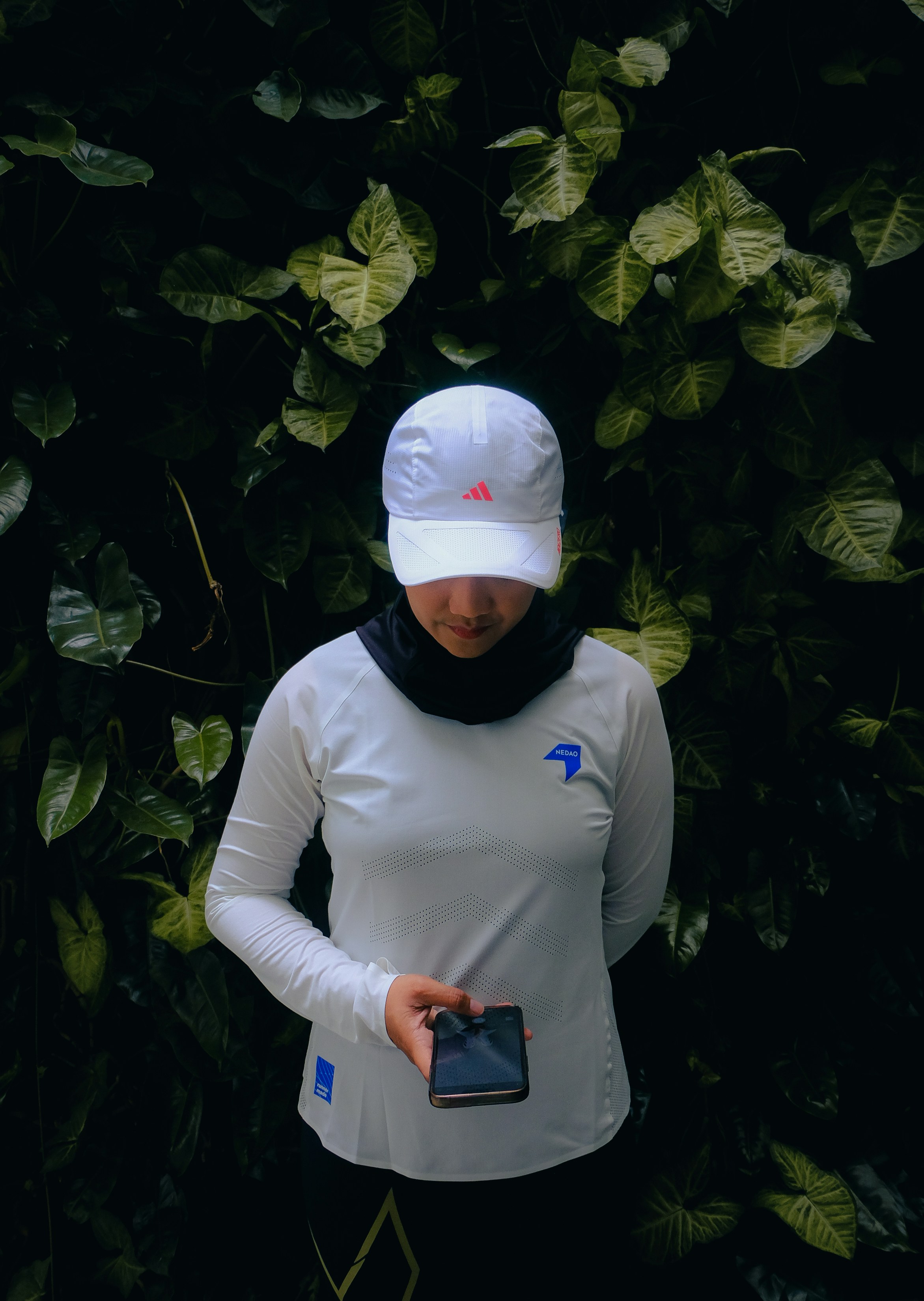 Woman in white hat and shirt holding phone