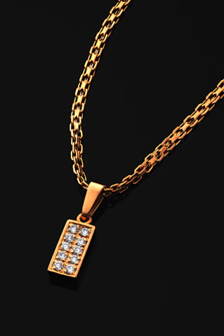 A gold necklace with a rectangular diamond pendant