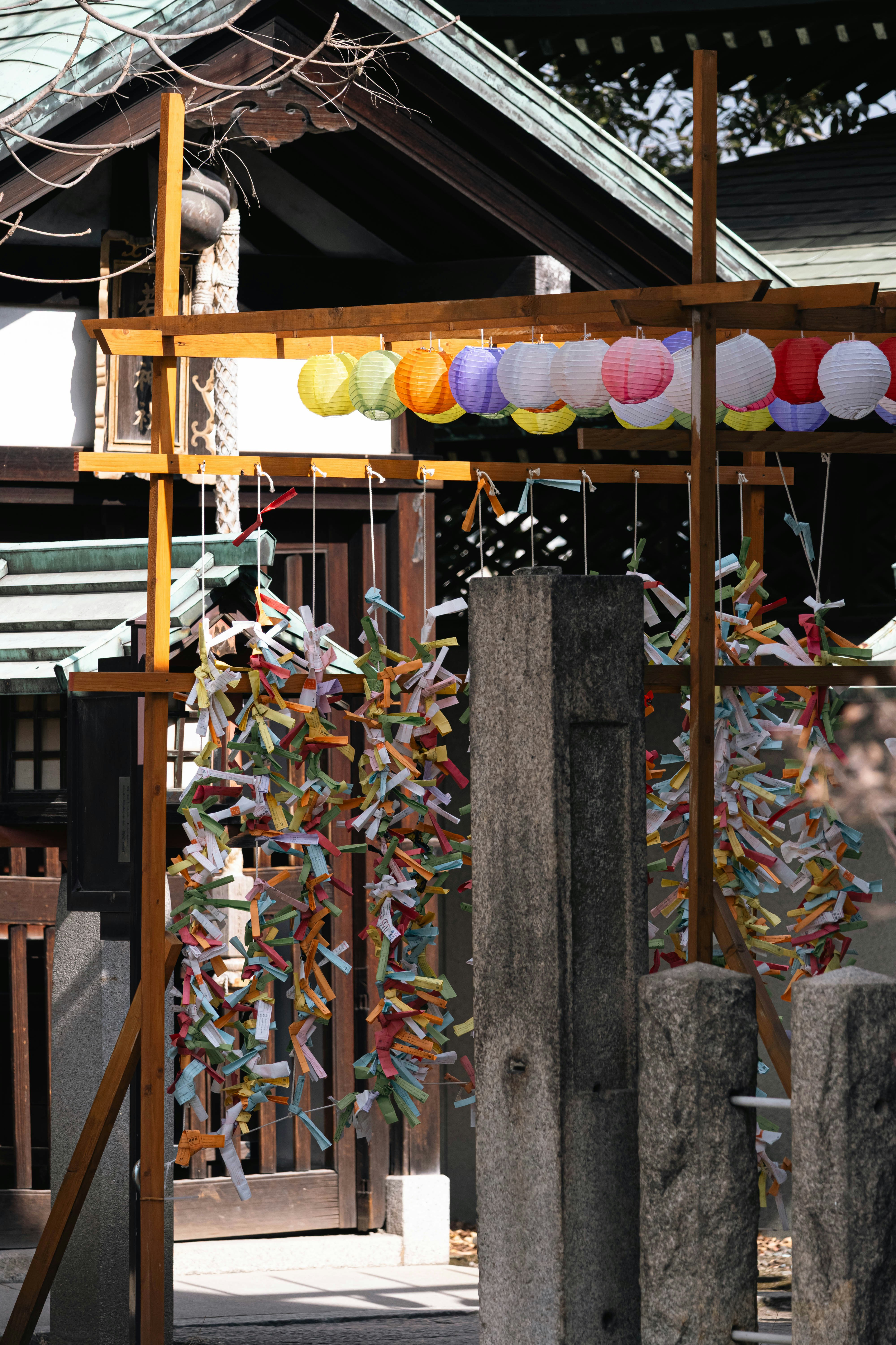 Des lanternes colorées et des papiers de fortune dans un sanctuaire.