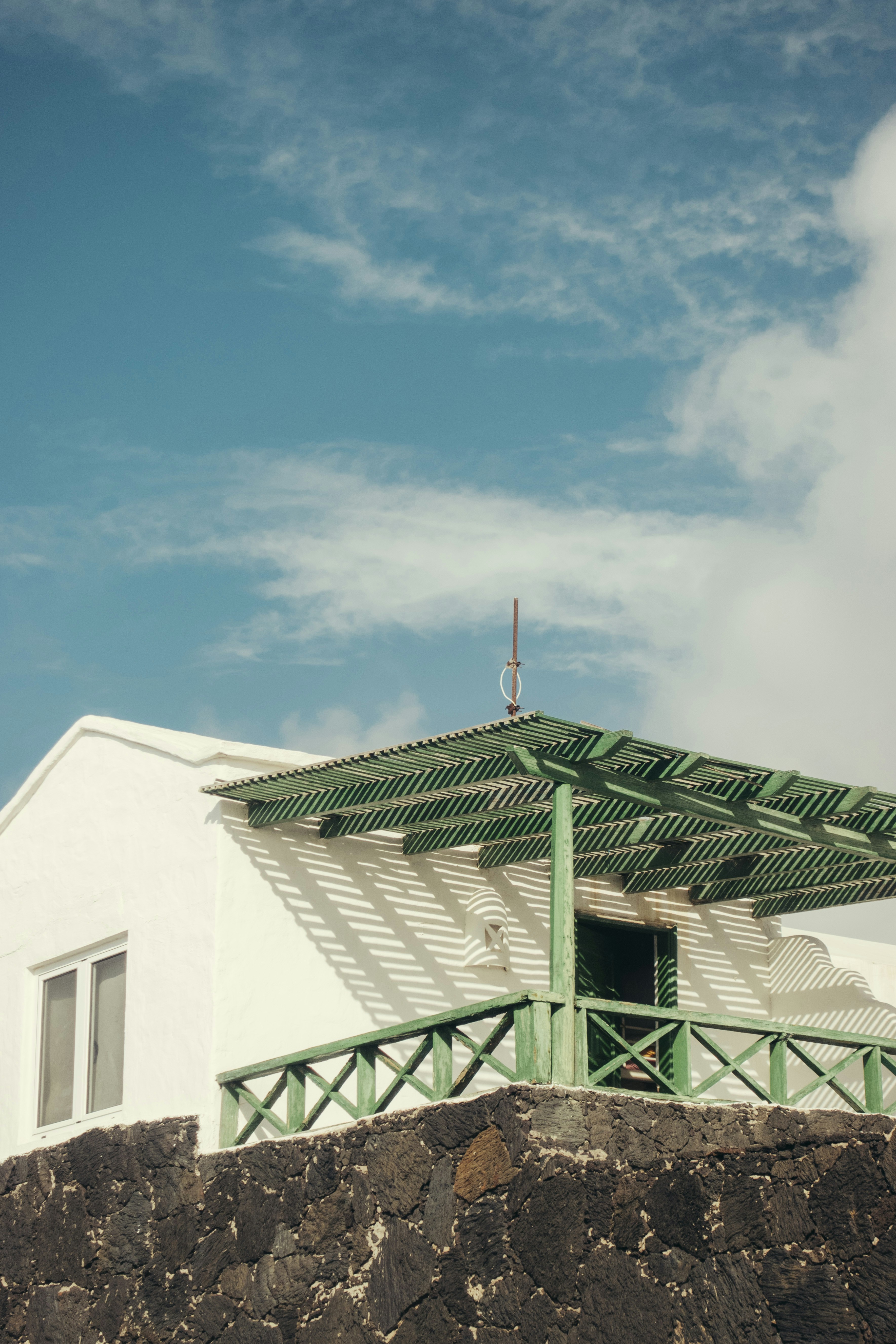 White house with green balcony and blue sky