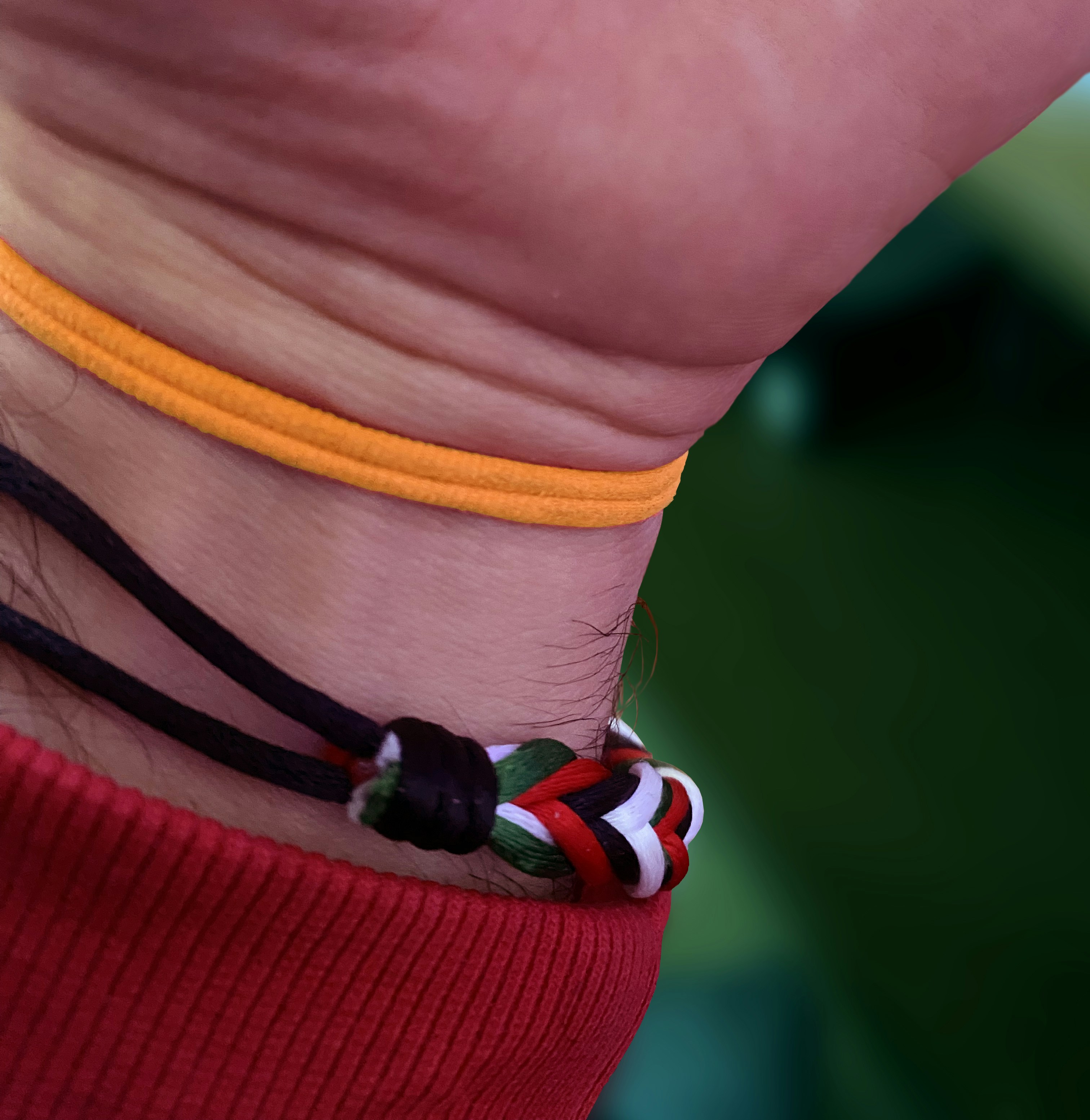 Nahaufnahme eines Handgelenks mit bunten Armbändern.