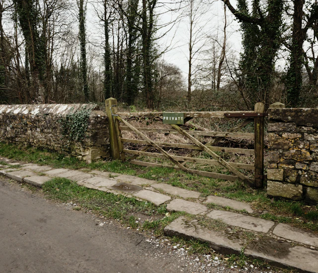 Wooden gate beside a stone wall in a rural setting
