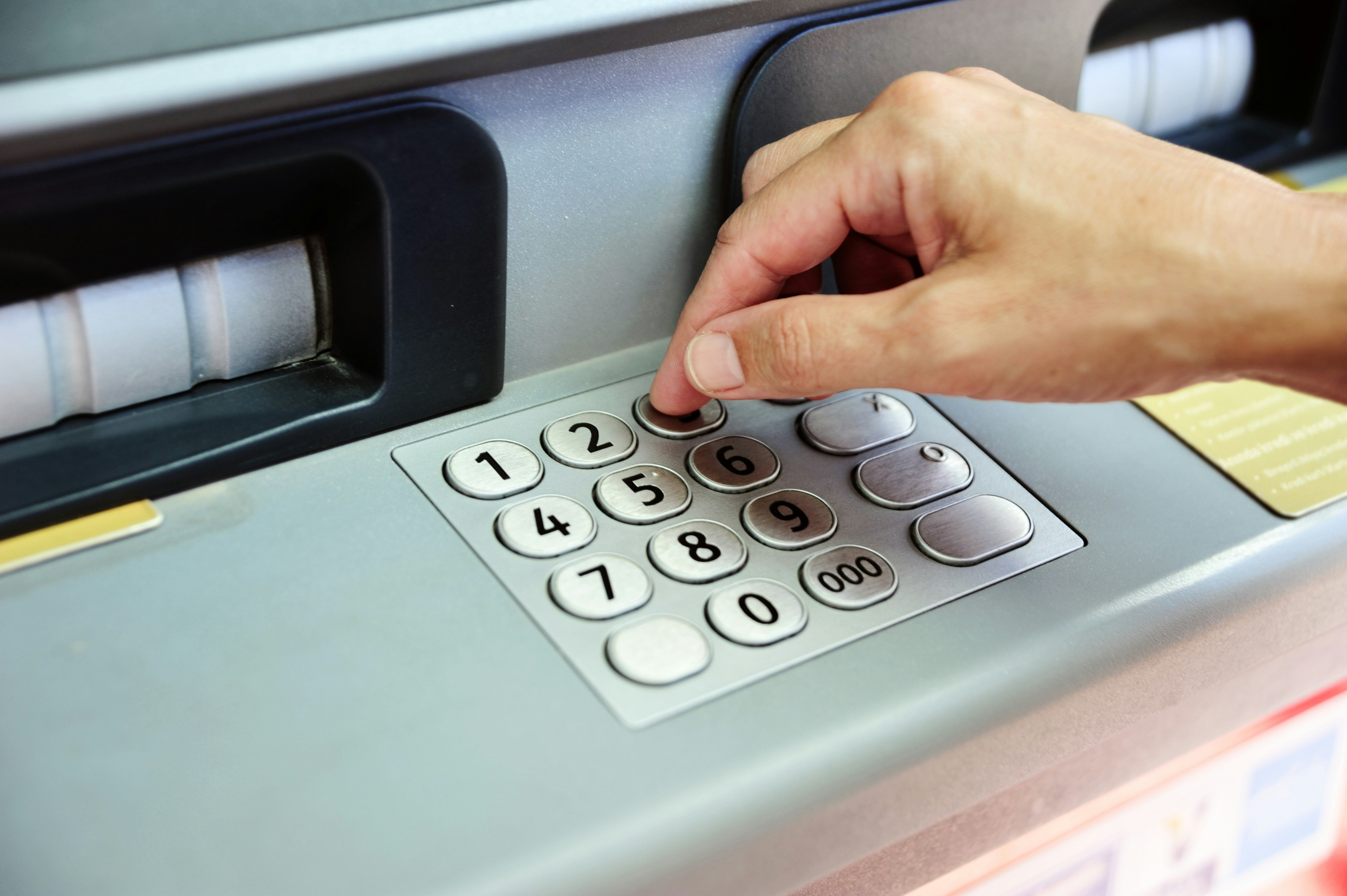 Hand entering pin code on atm keypad