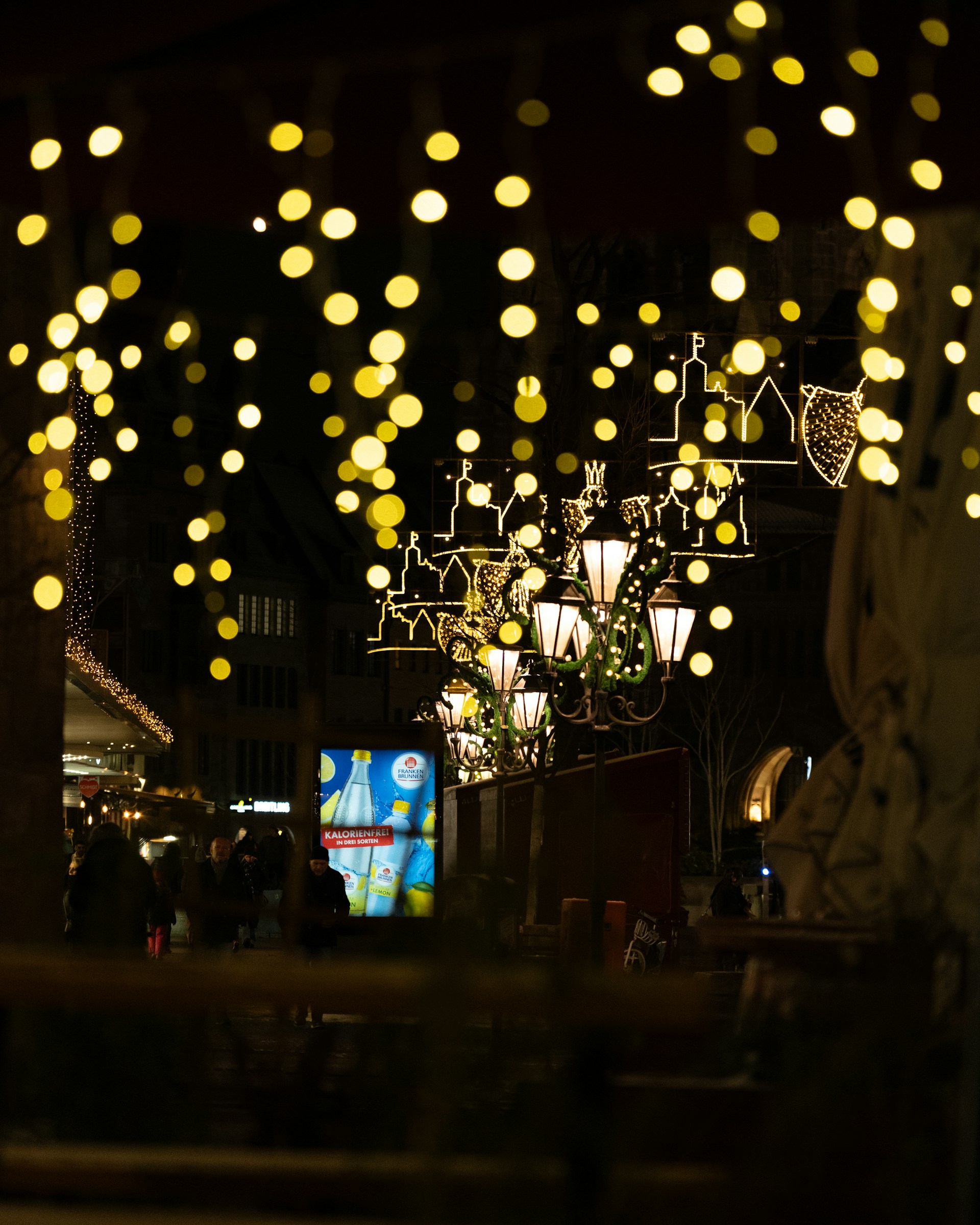 Streetlights and hanging lights illuminate a dark street