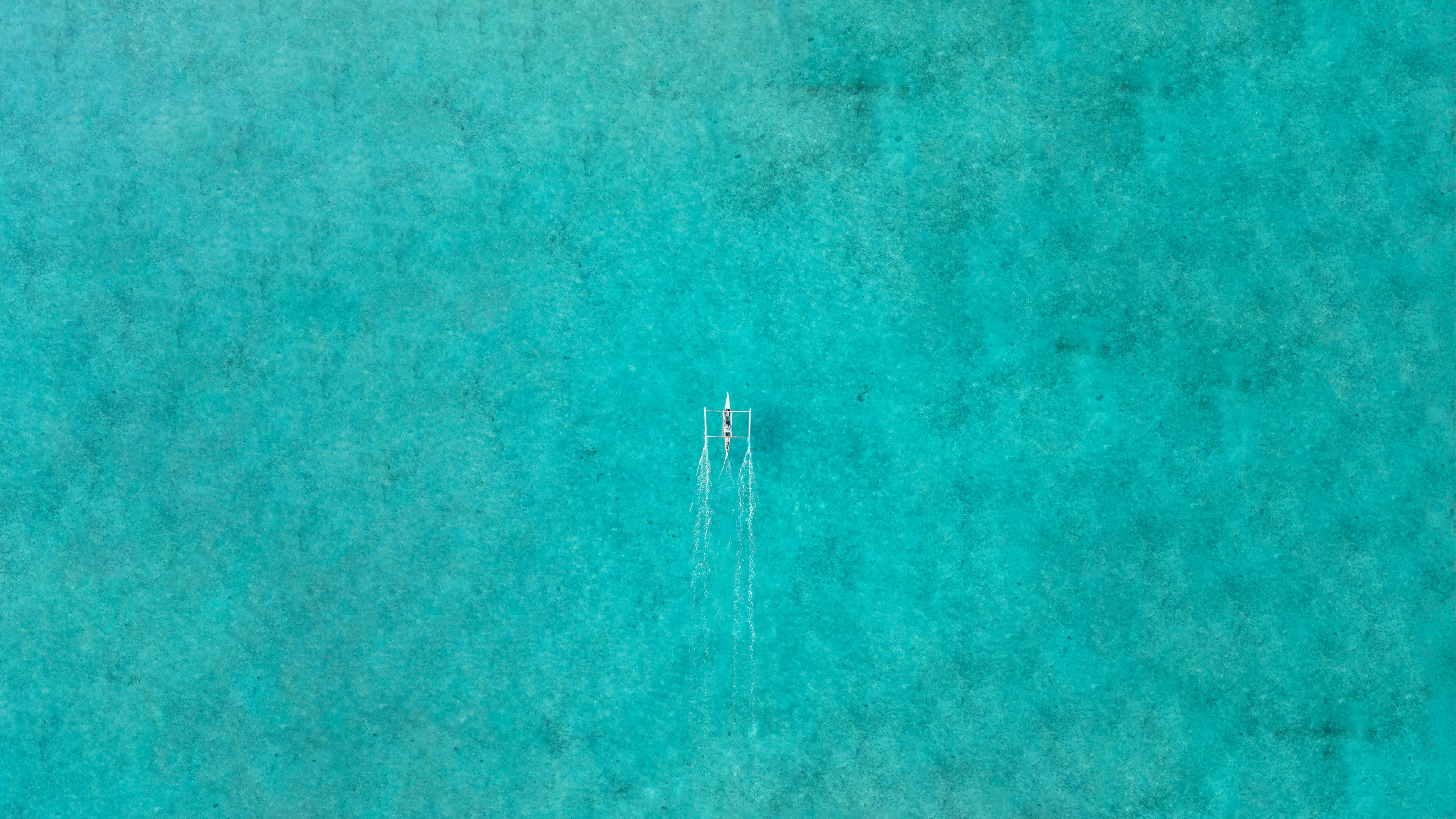 A small boat leaves a wake on turquoise water