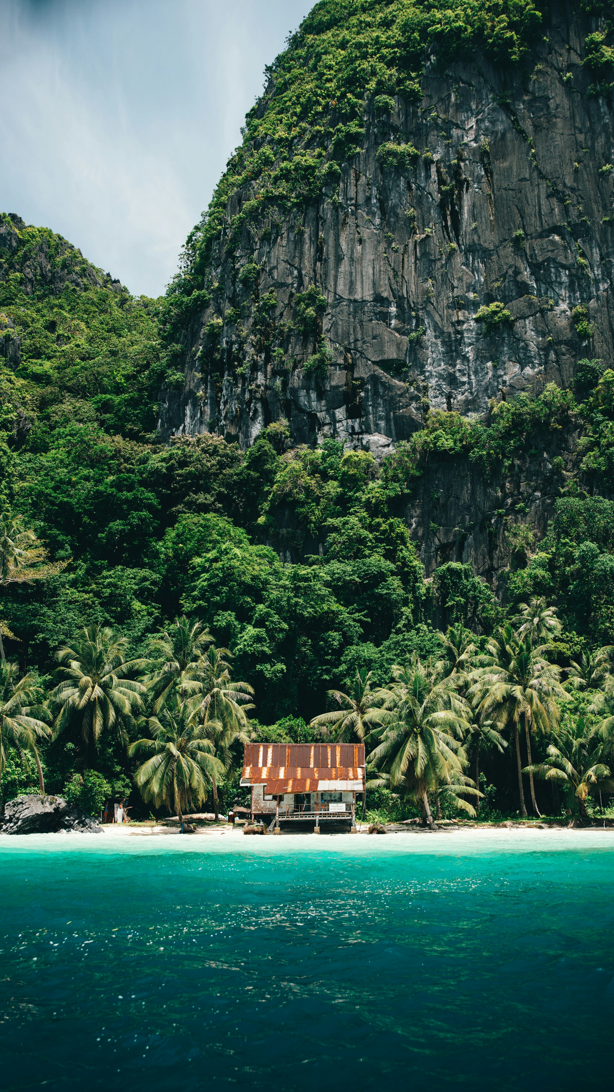 Abandoned shack on a tropical beach with turquoise water.