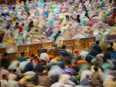 Blurred crowd of people praying together in unison.