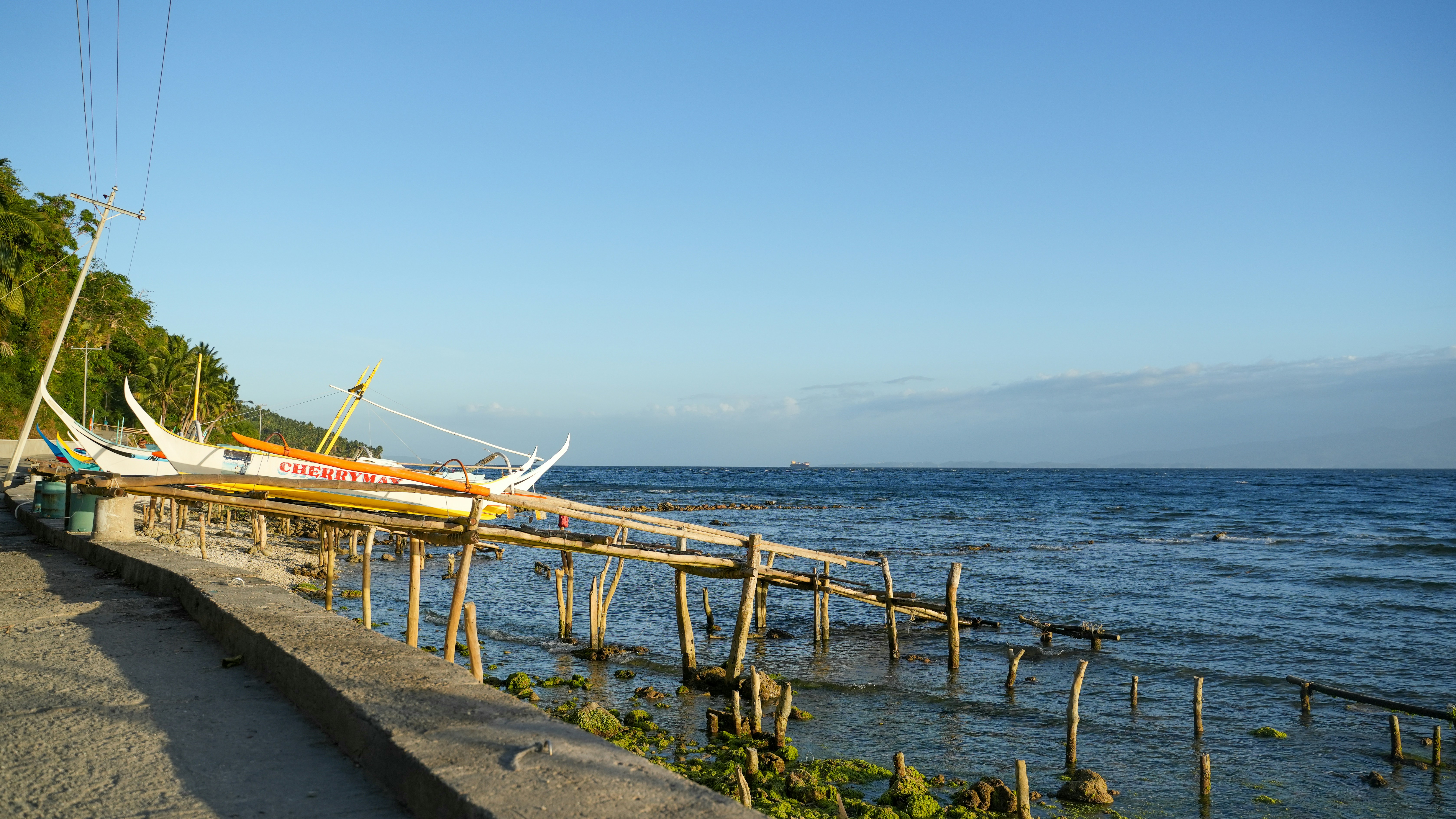 A wooden pier with boats by the ocean