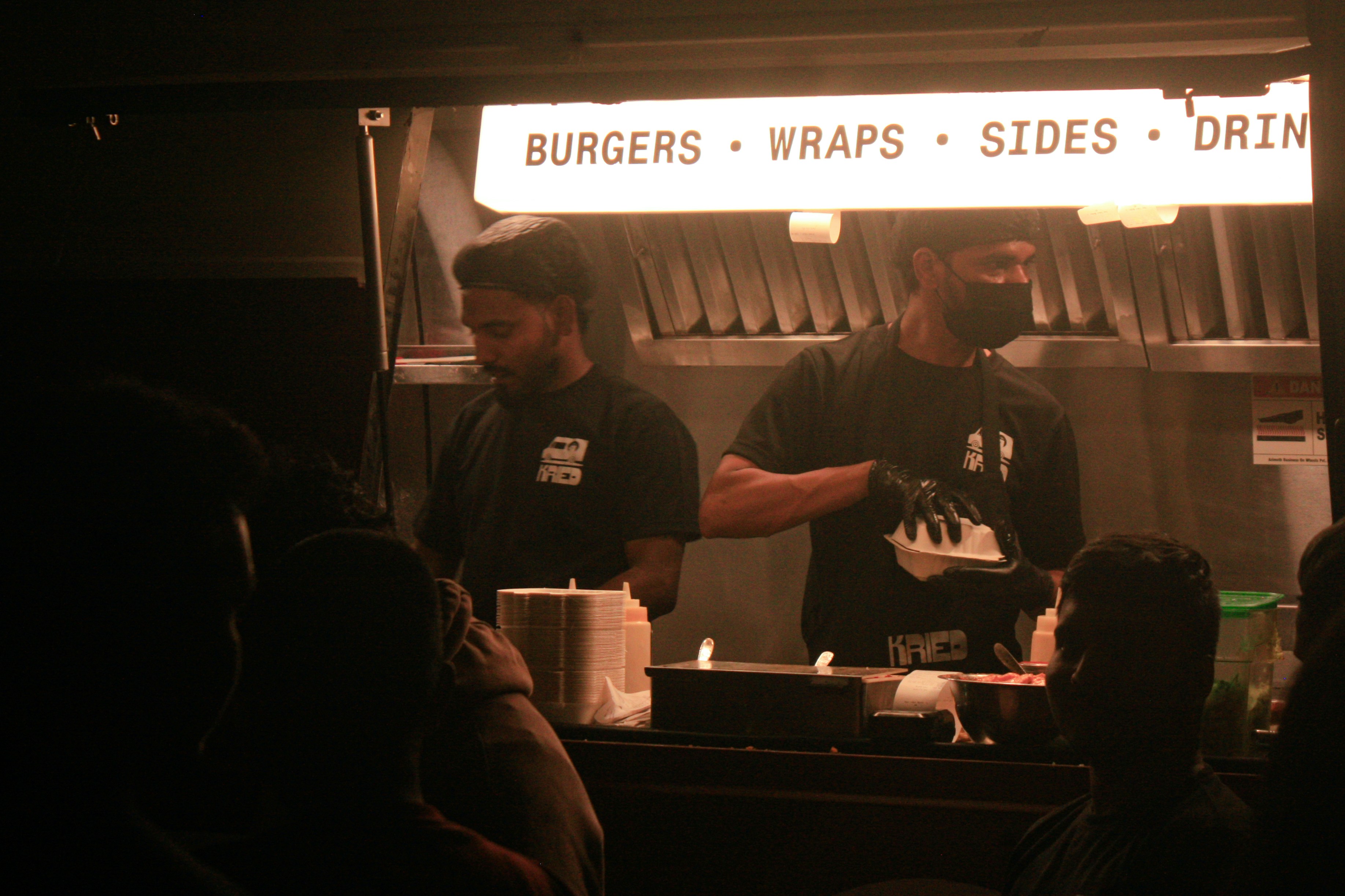 Two men working at a food truck window.