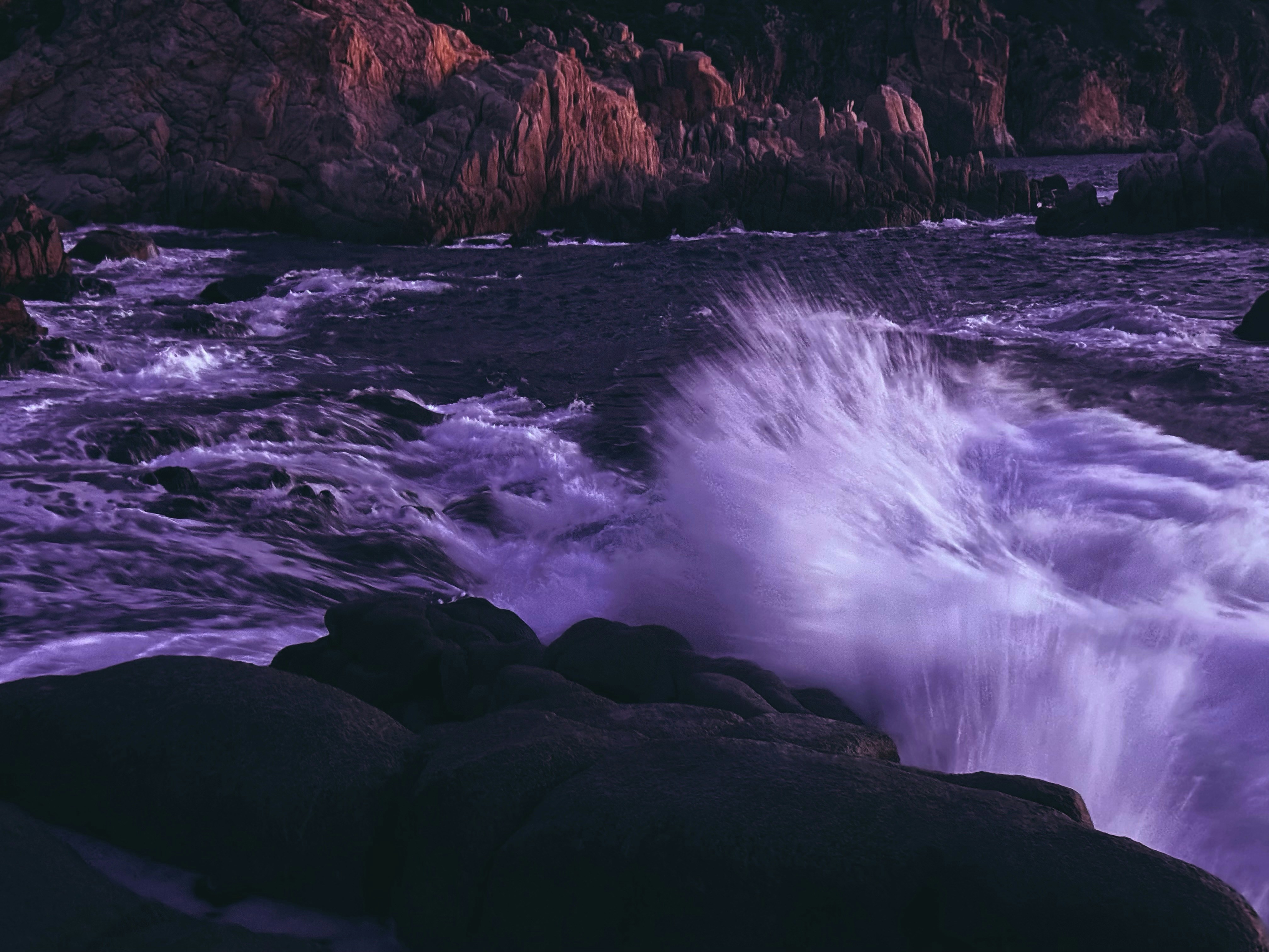 Waves crashing against rocky shore at dusk