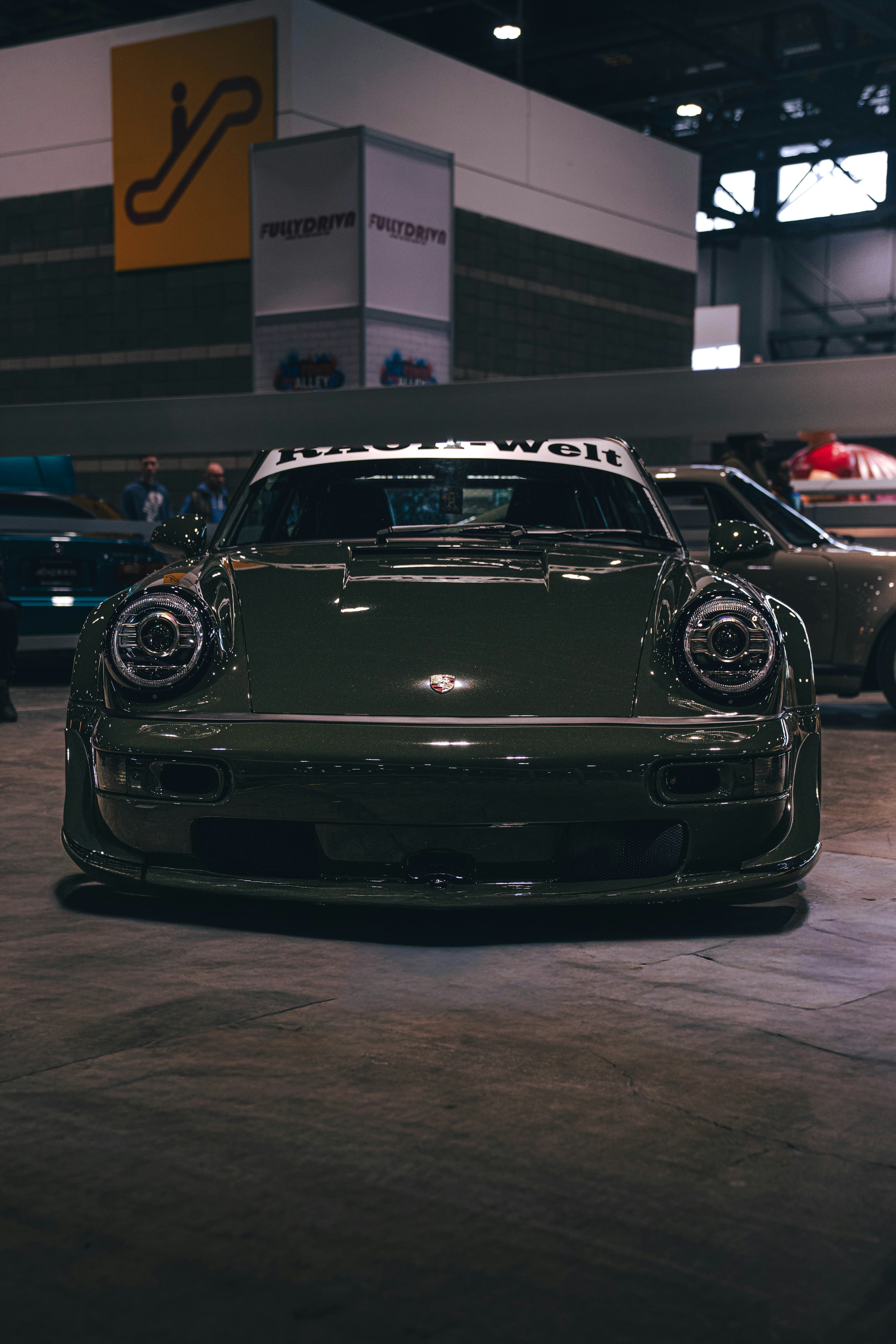 A dark green vintage porsche 911 at a car show.