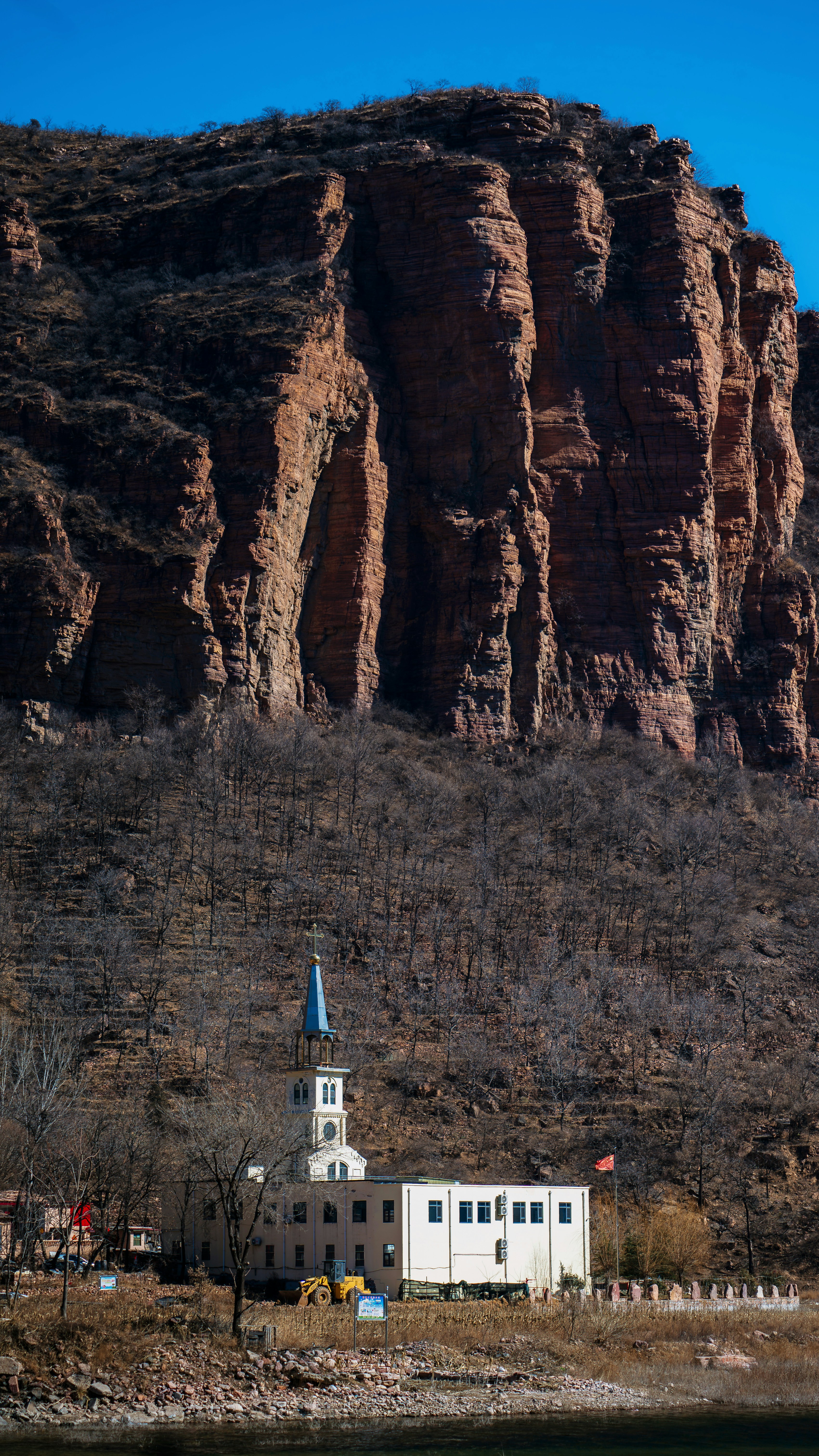 A church sits at the base of a large cliff.