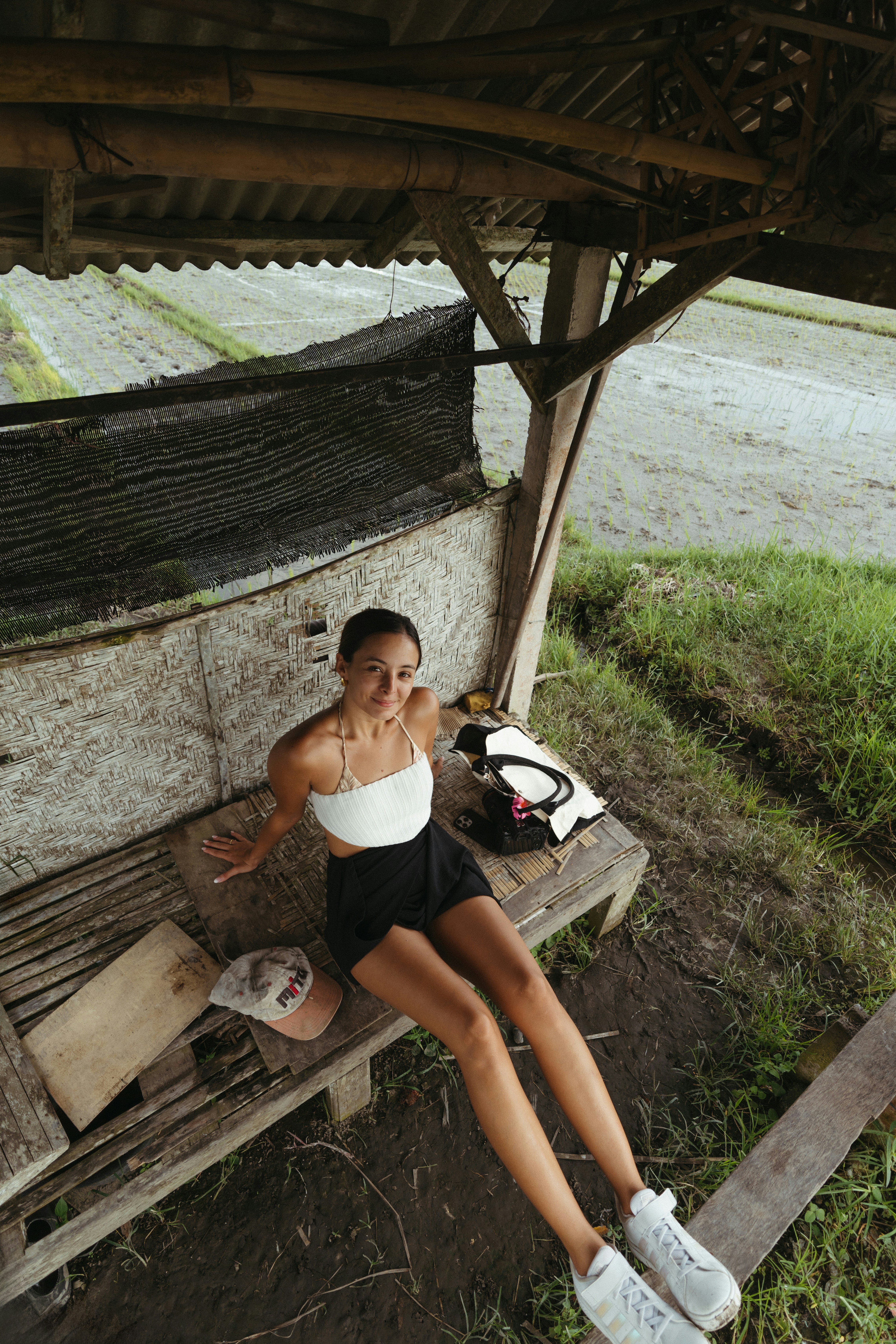 Jovem relaxando em um banco rústico de madeira ao ar livre.