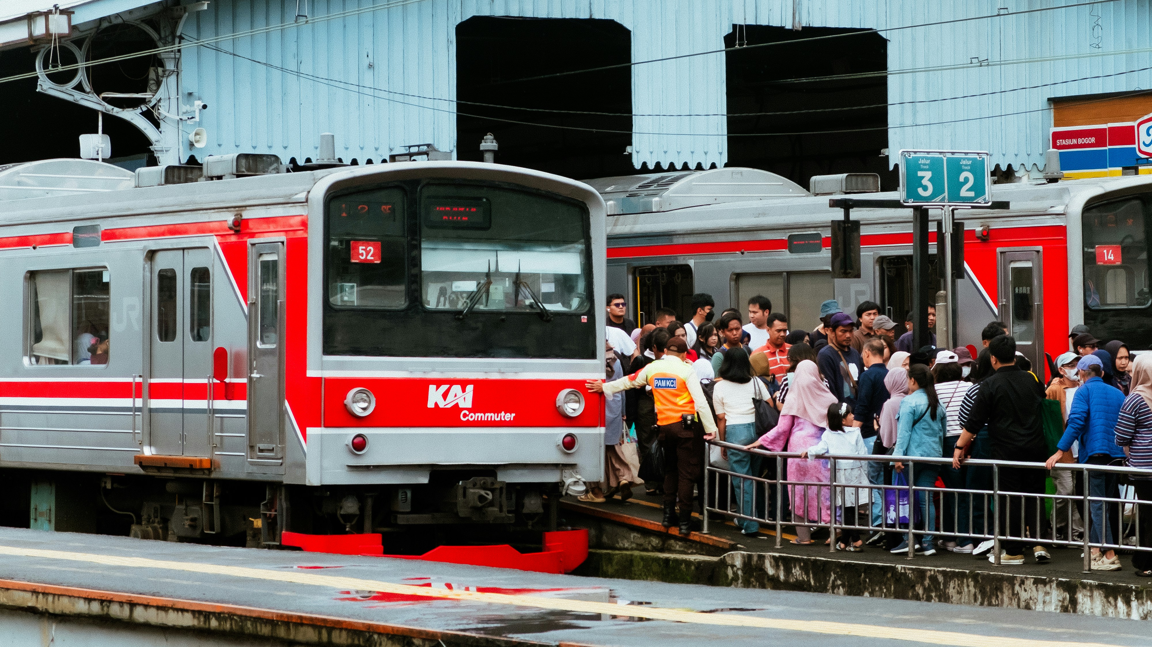 Komuter menunggu kereta di stasiun yang sibuk.