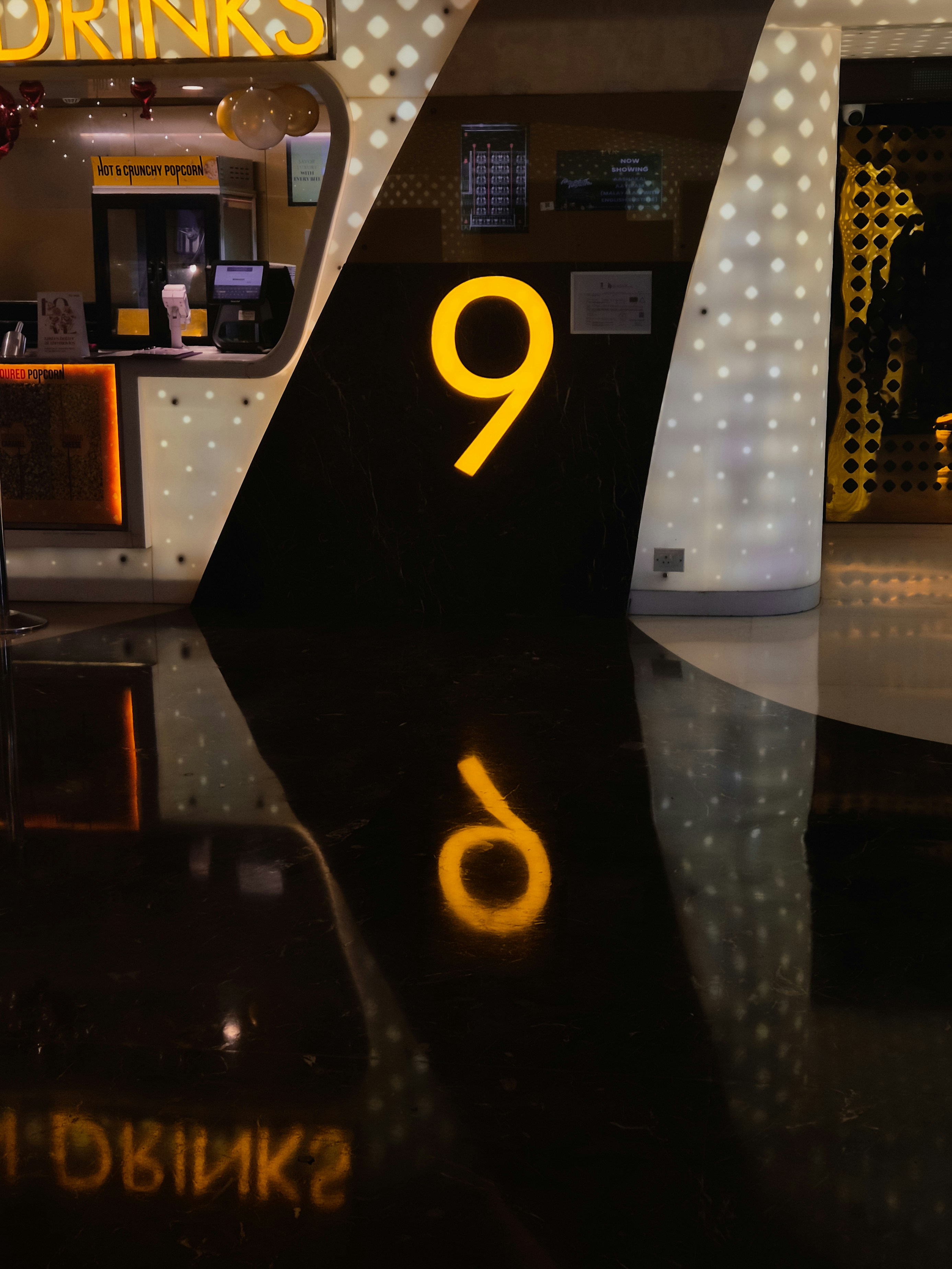 A glowing number nine reflected on a shiny floor.